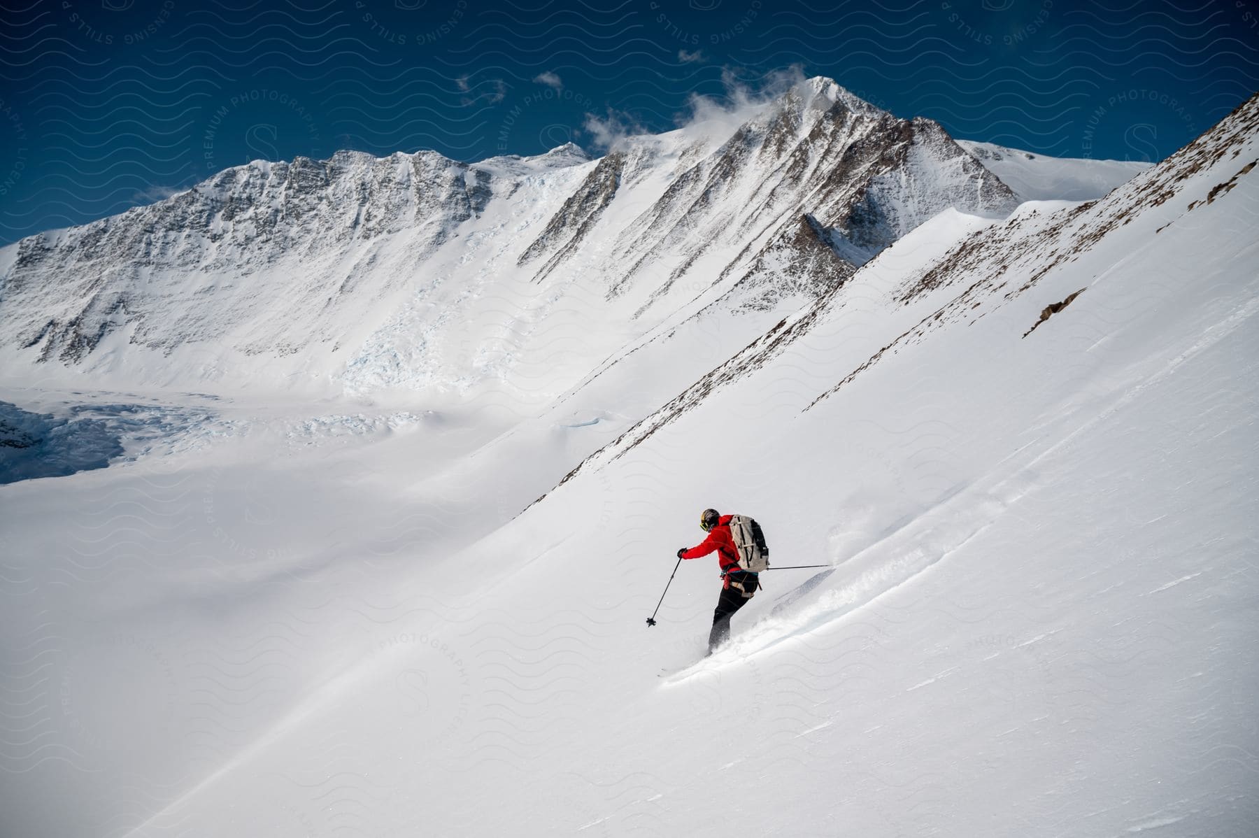 A skier descends a mountain slope kicking up powdery snow