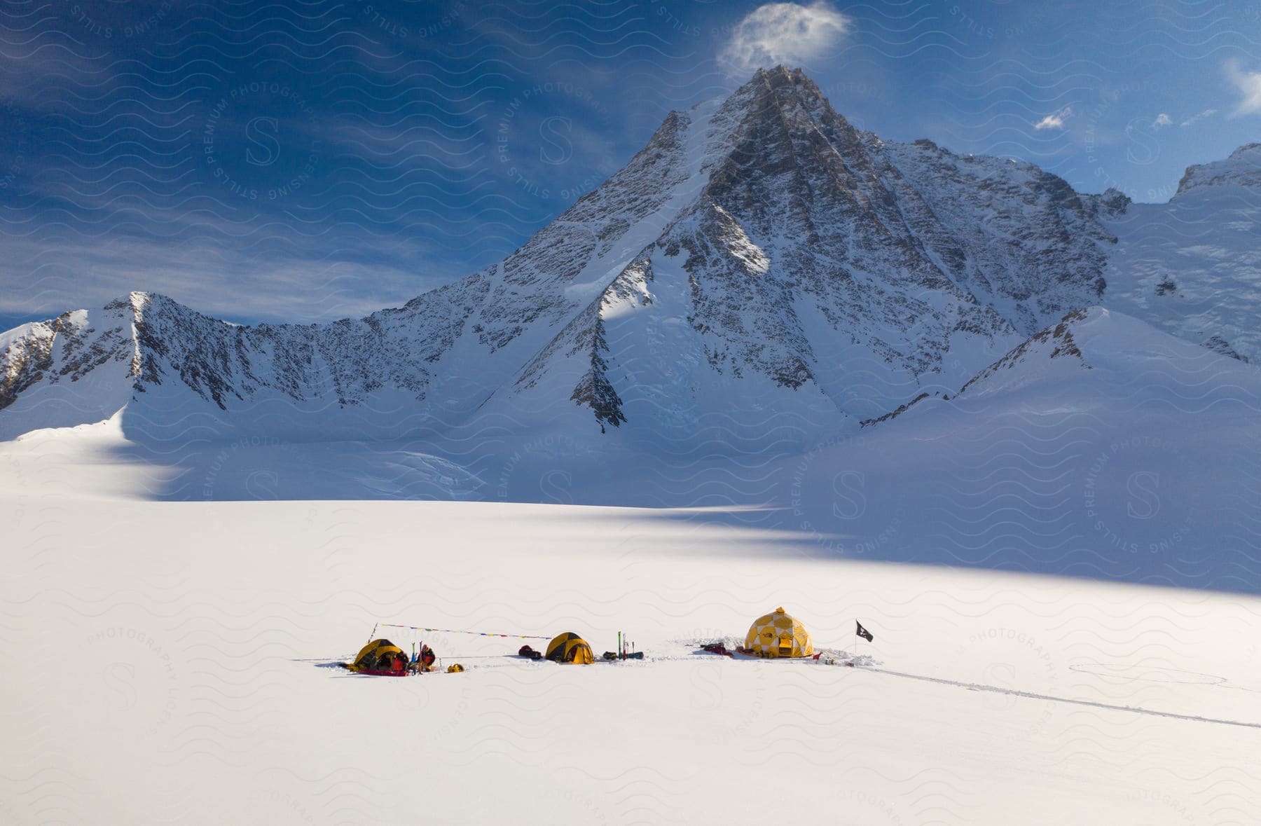 Three tents in the snow next to a mountain range in antarctica