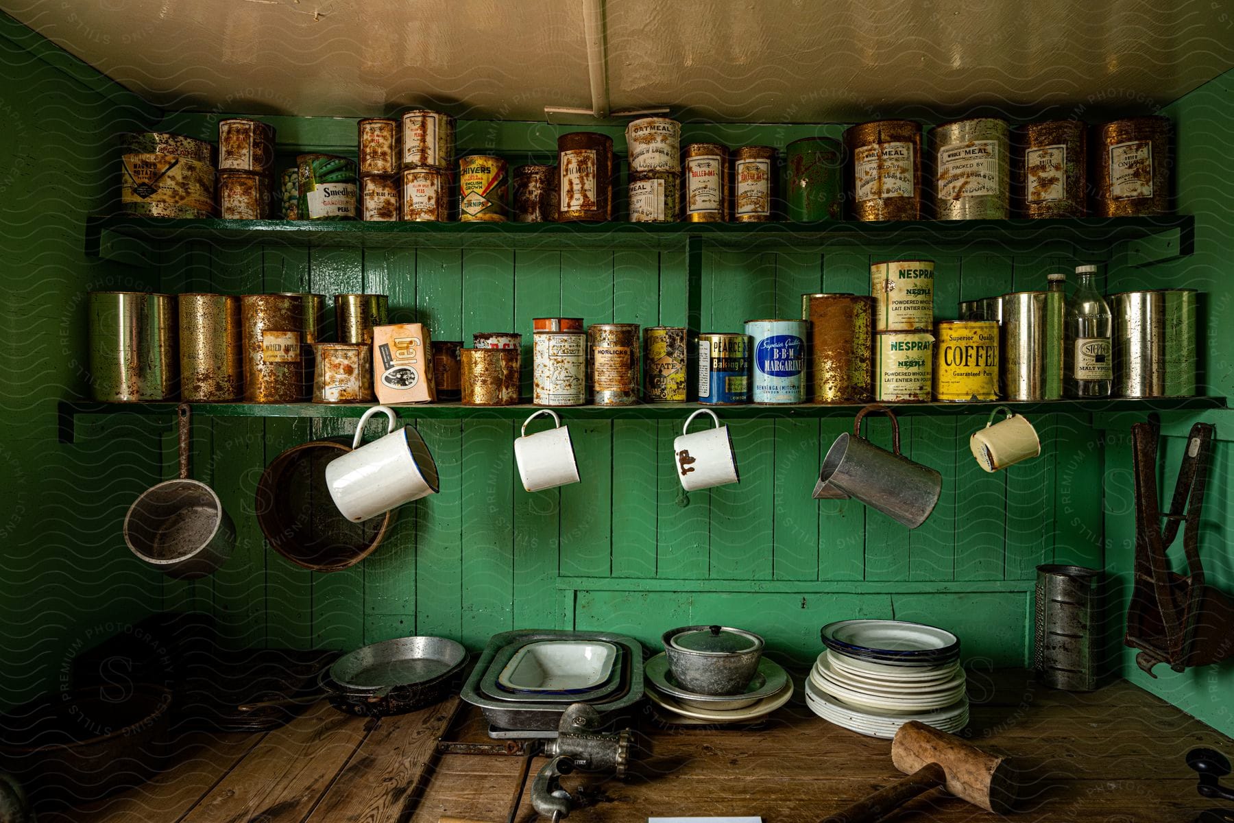 Vintage coffee cans on shelves in a green room with vintage cookware on a wooden counter