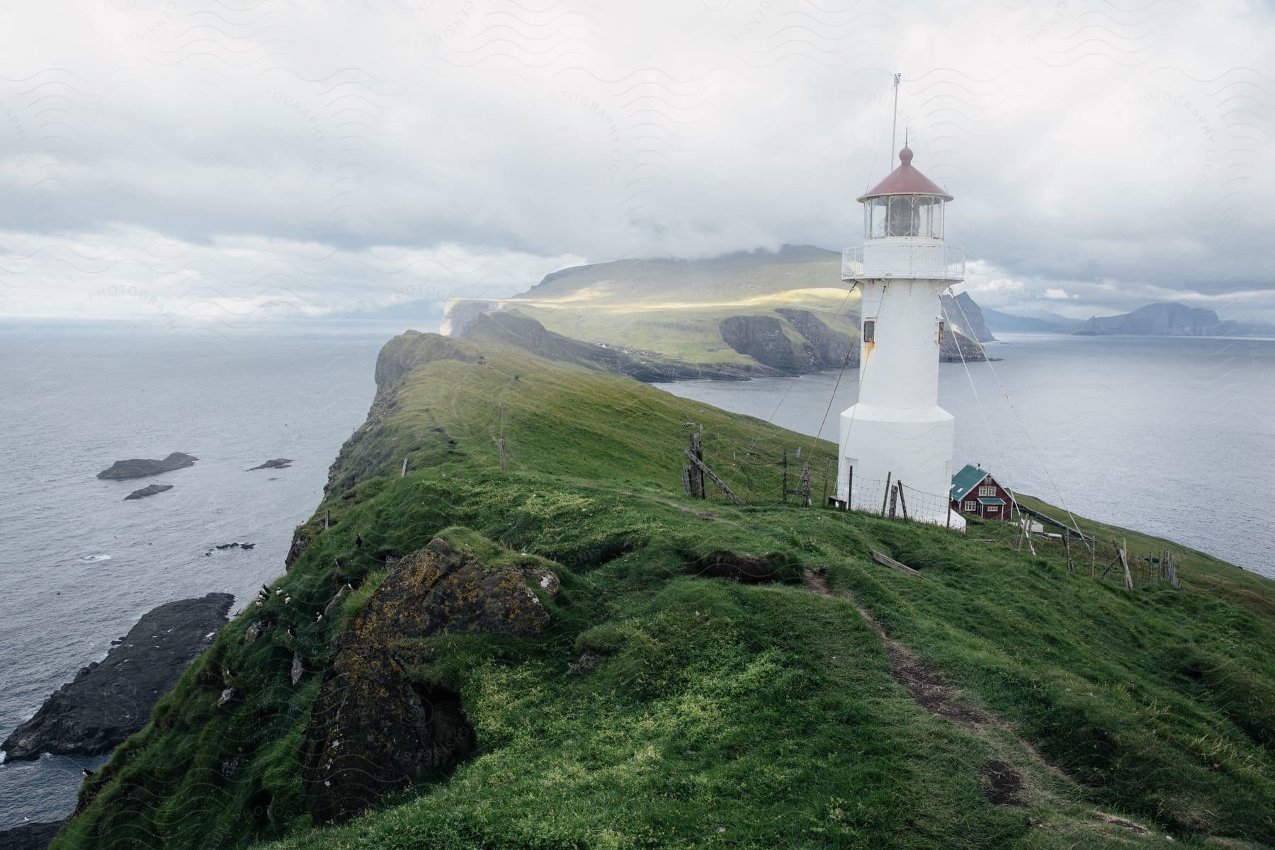 A white building on a rocky outcrop by the waters edge creating a stunning coastal scene