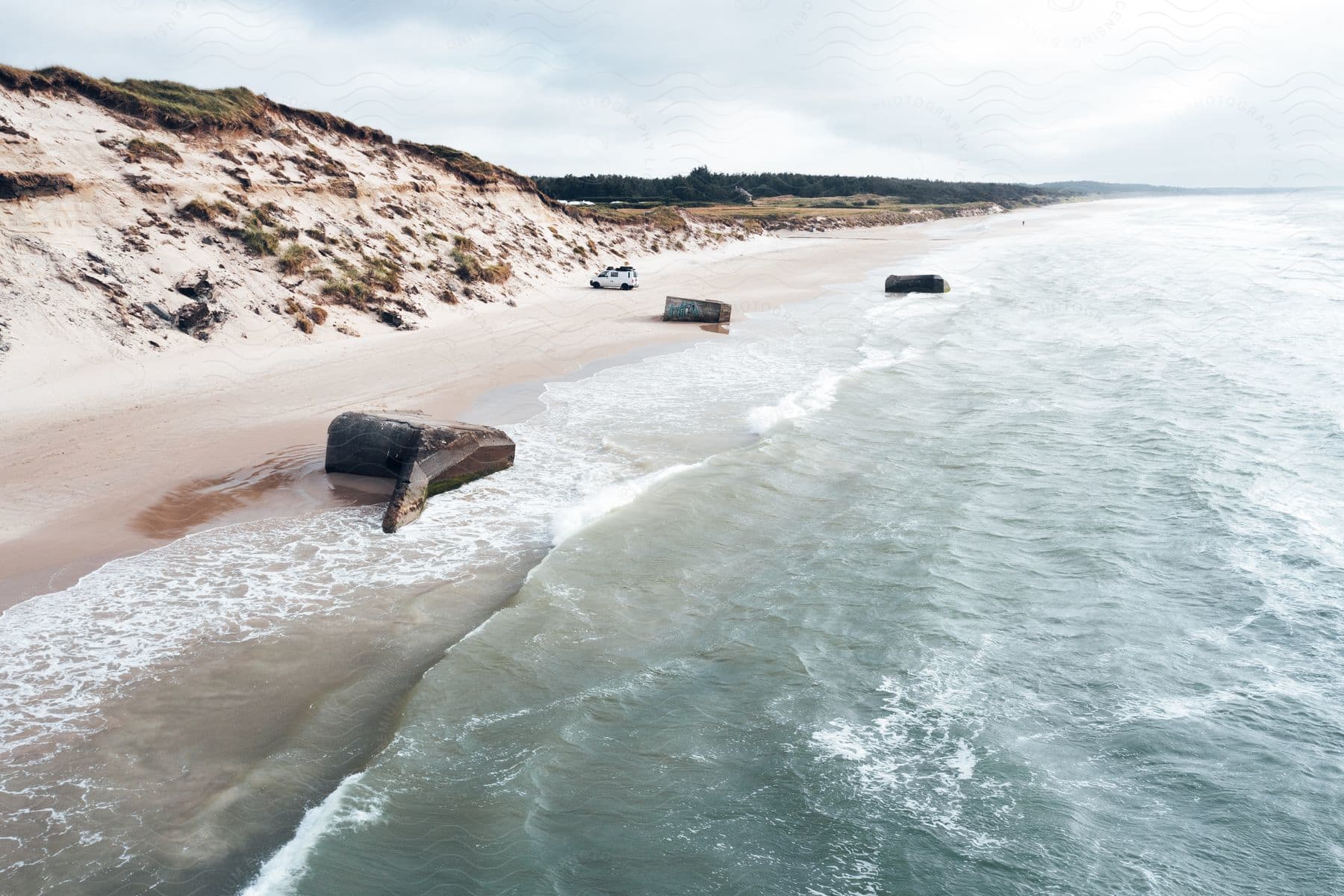 Aerial view of the coastline and beach with a sky filled with clouds and a watercourse