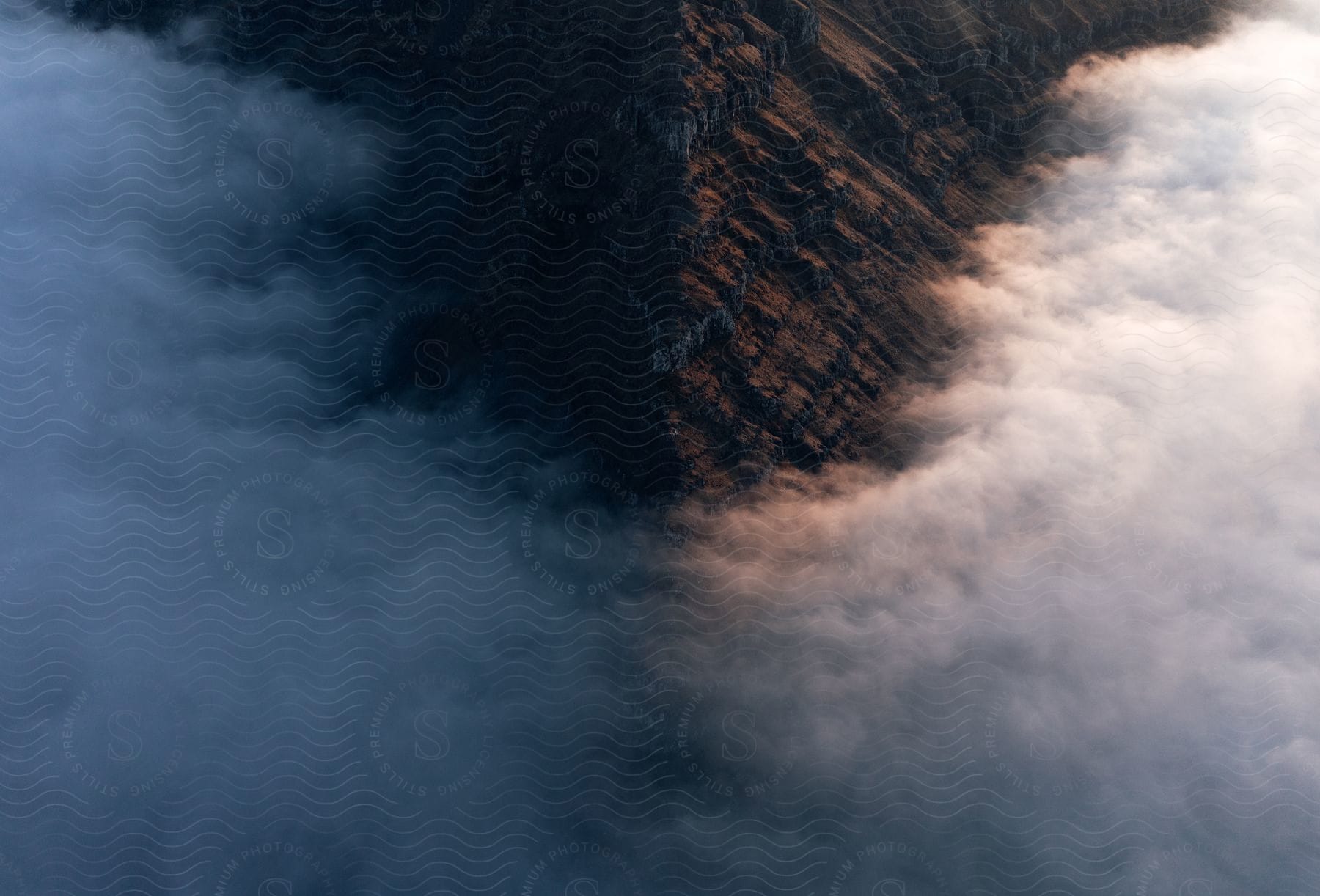 Clouds surround a mountain in an aerial shot