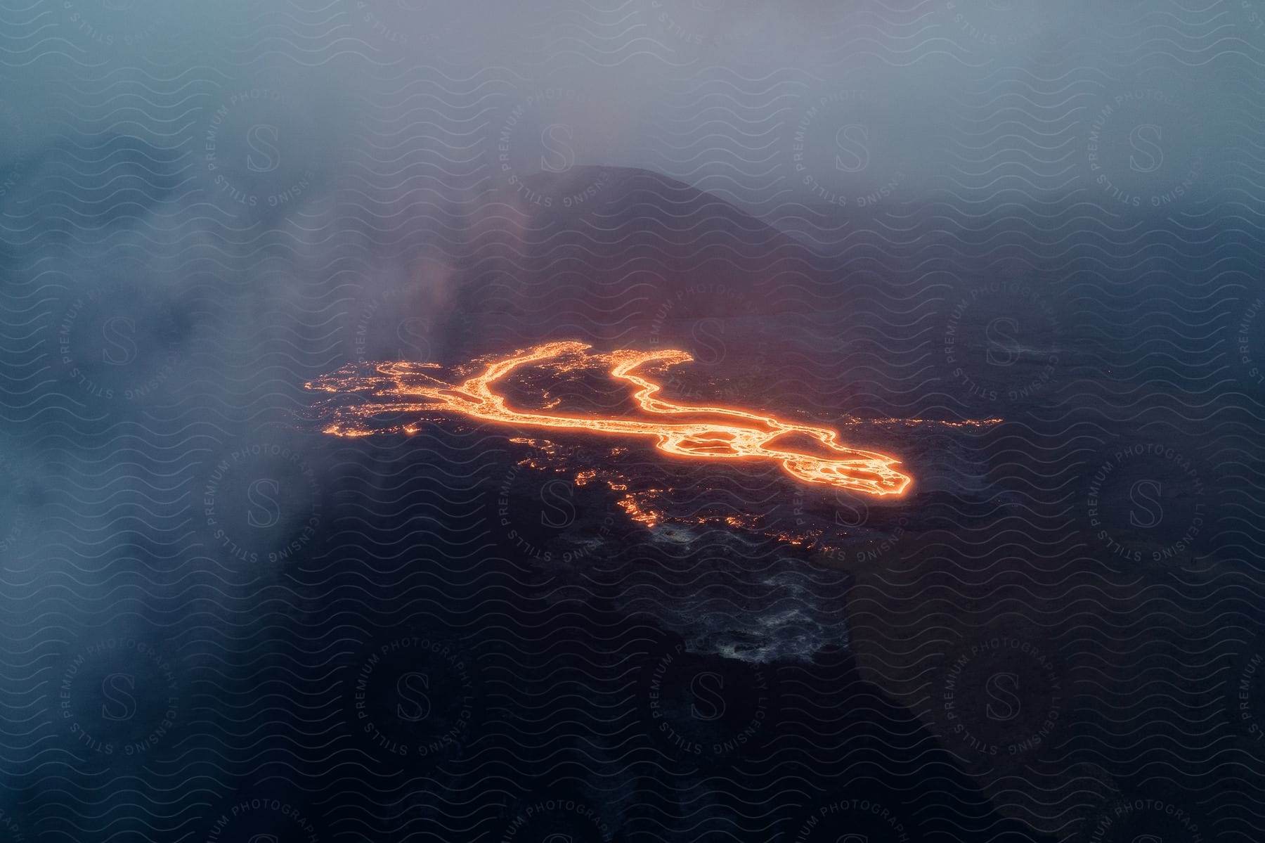 A serene landscape of a volcano in iceland during the summer with a clear sky clouds and a body of water in the background