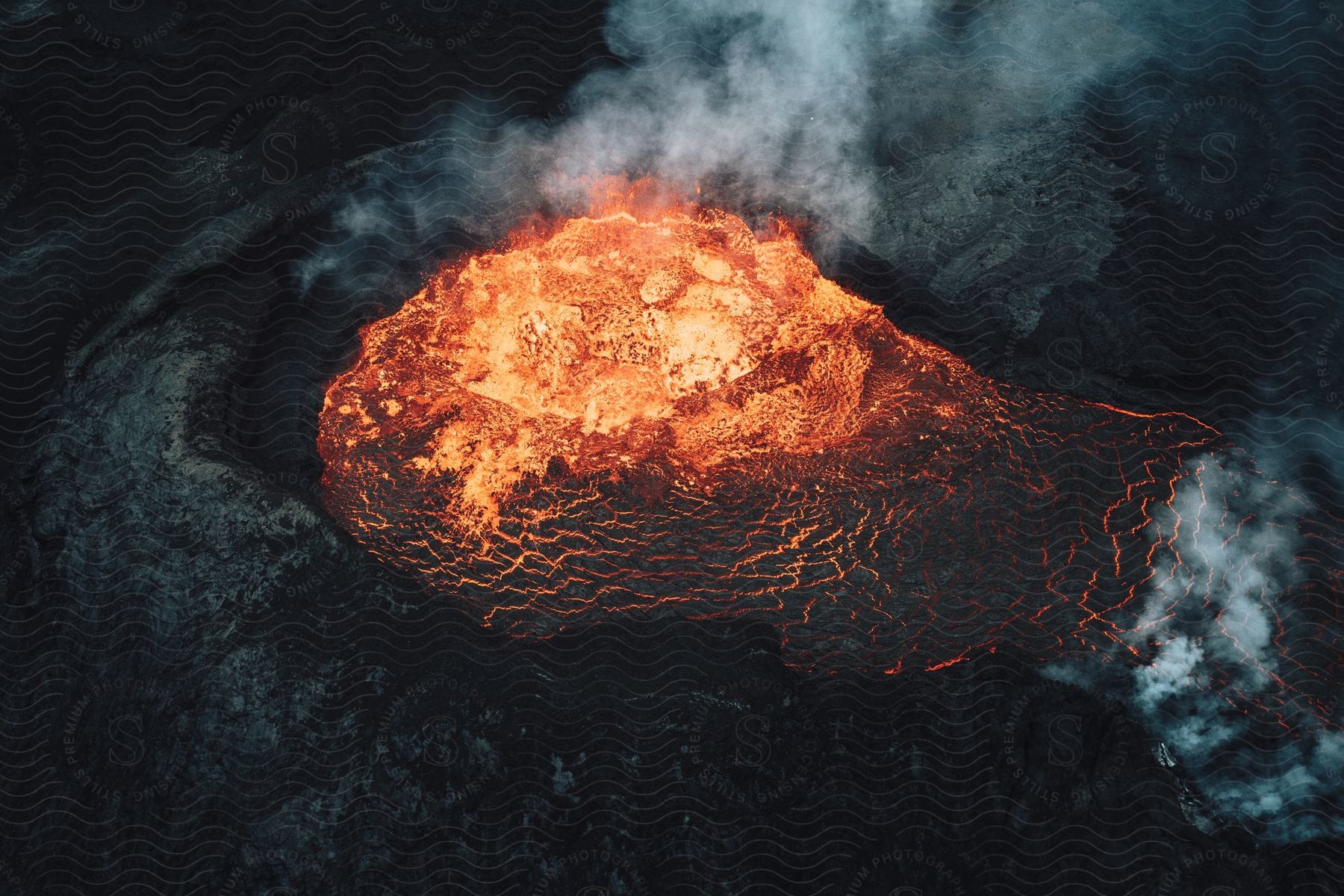 Smoke rises from an erupting volcano as glowing hot lava flows