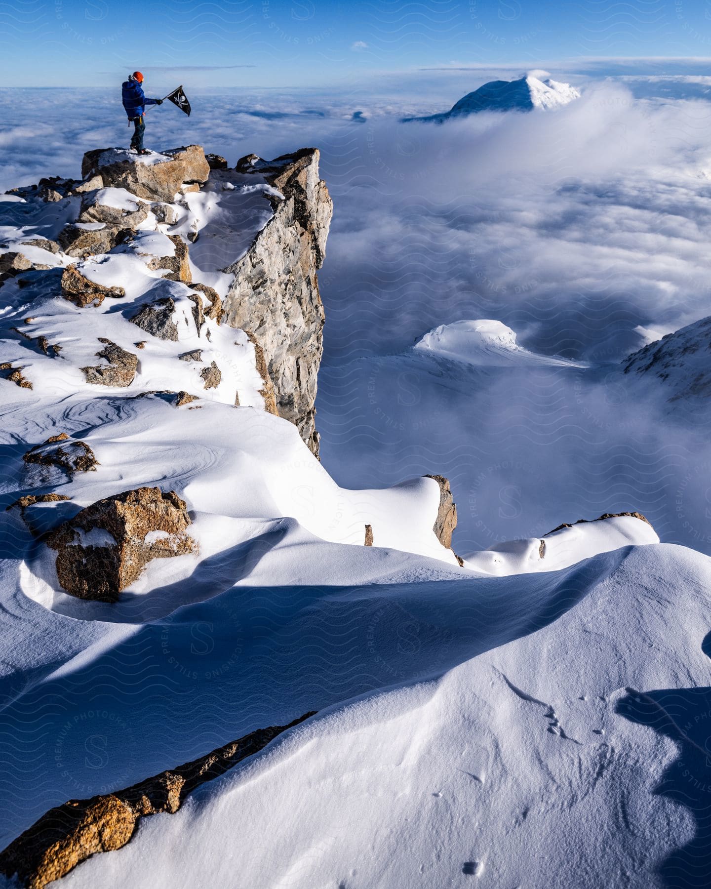 A person stands on top of a snowy mountain in foggy conditions