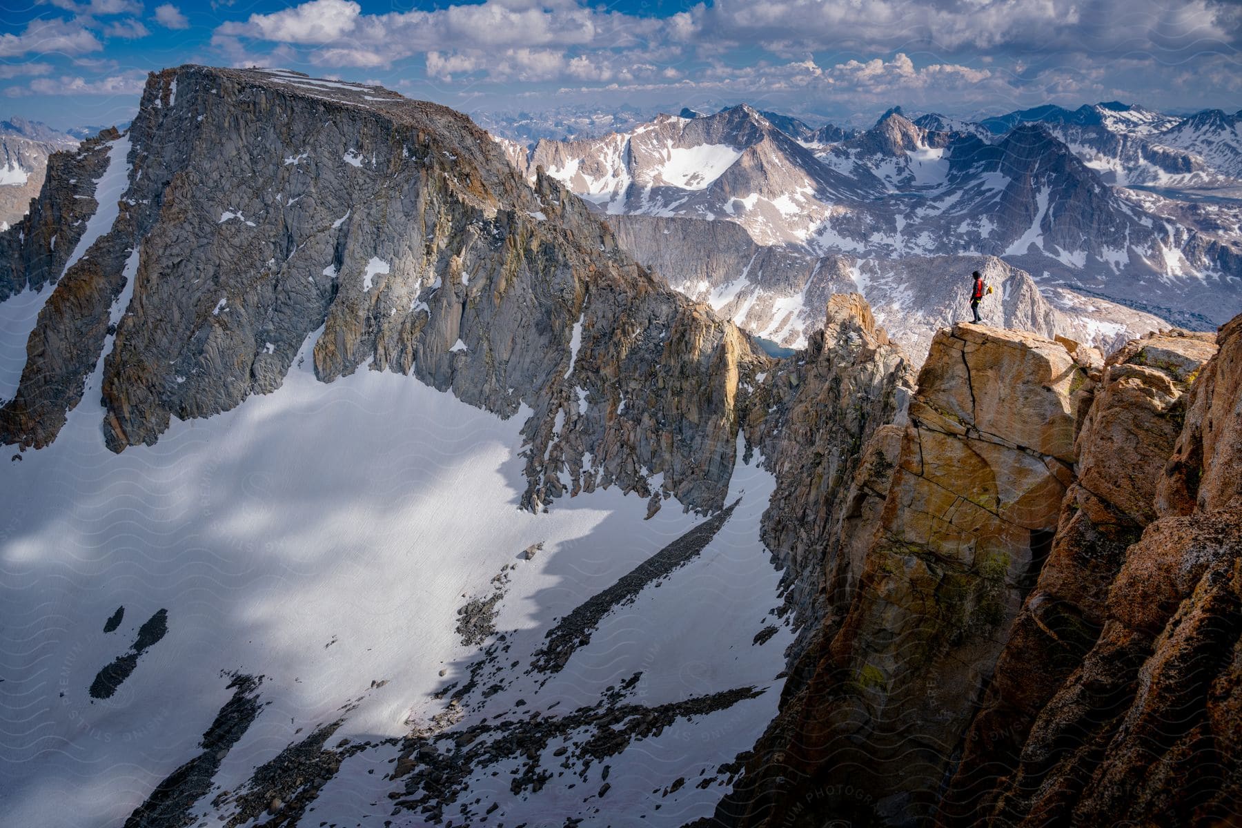 Distance hiker stands on mountain ridge looking over snowy mountains in the high sierras of california