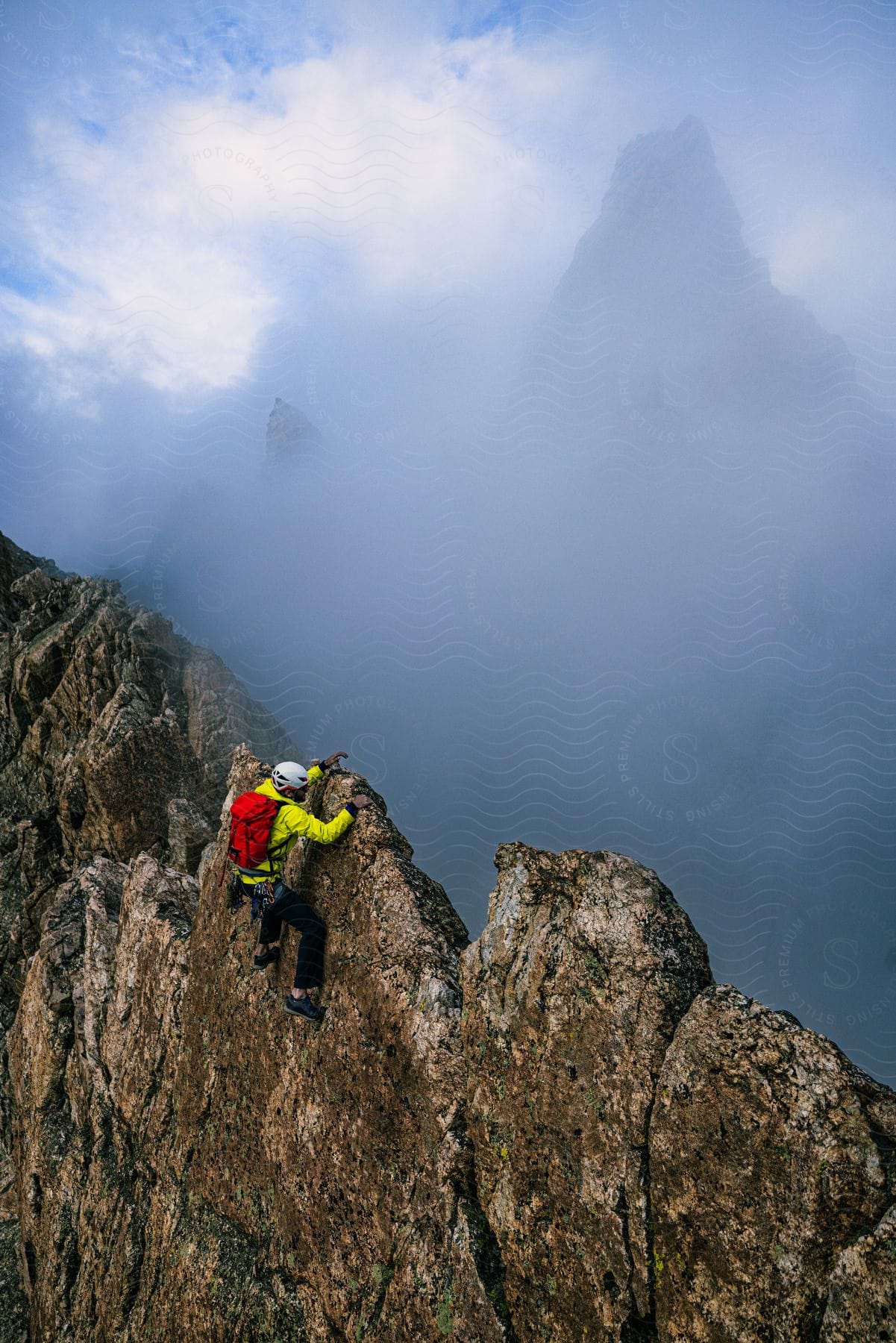 Climber ascending foggy mountain with other obscured peaks in the background