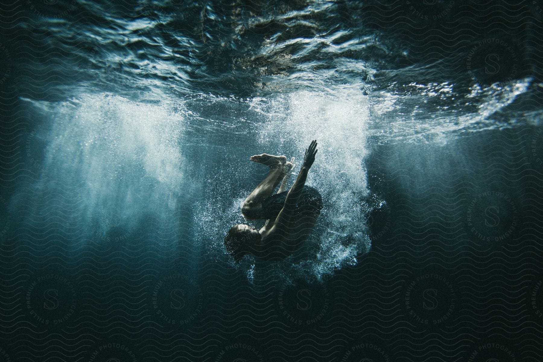 A male person diving into the water and performing a flip