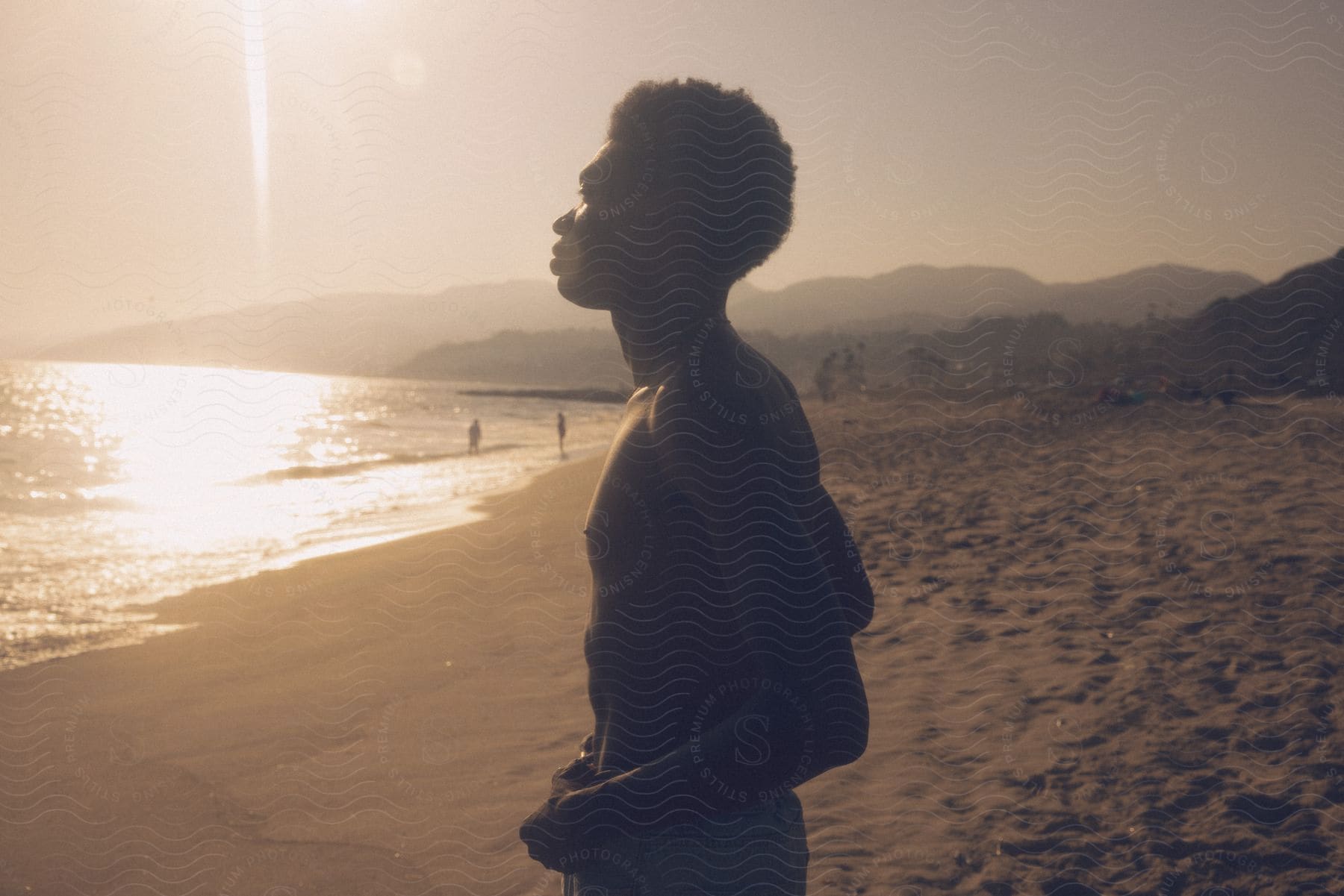 A person standing on a beach at dusk with a happy expression