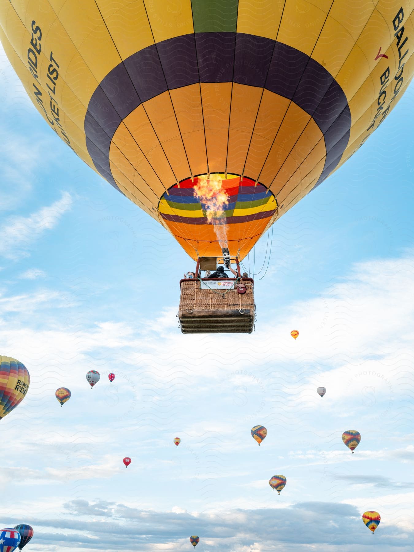 Several hot air balloons dot a cloudy sky