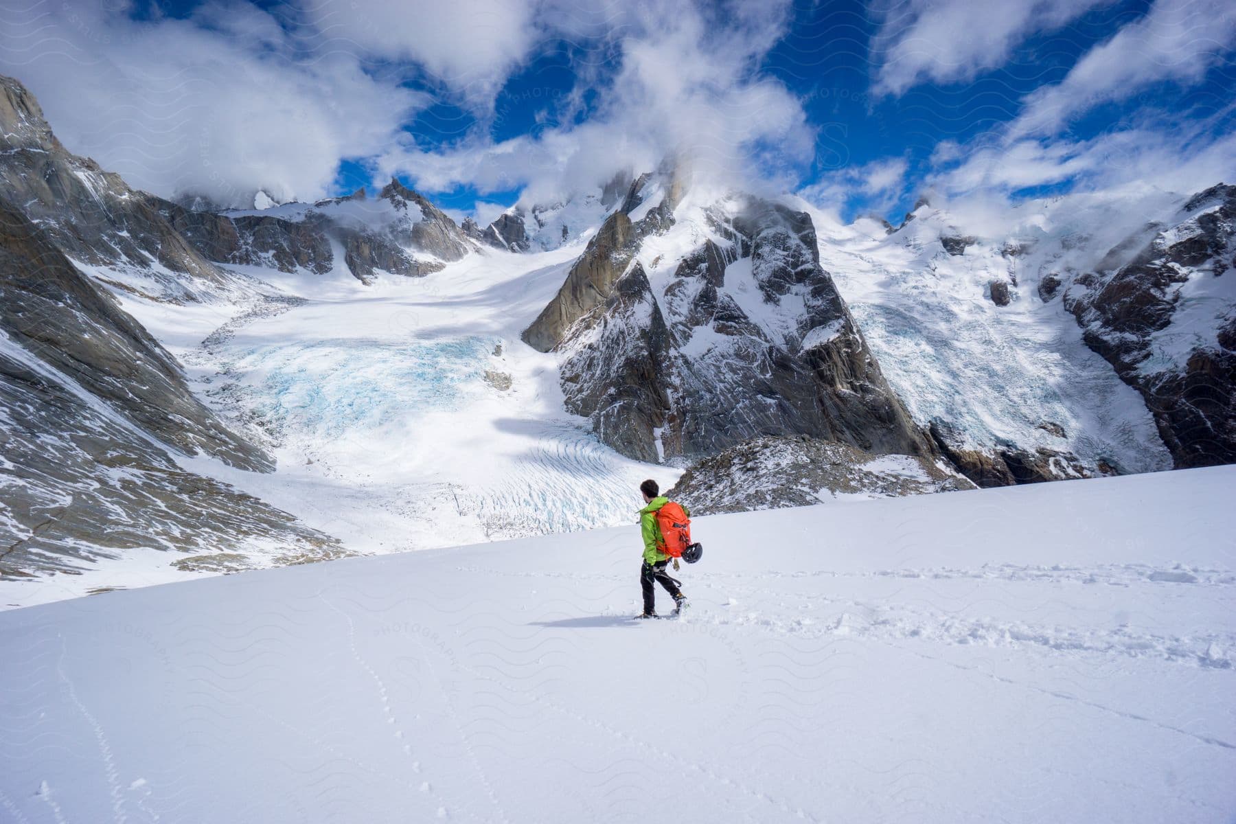 A person walking in the snow near snowy mountains