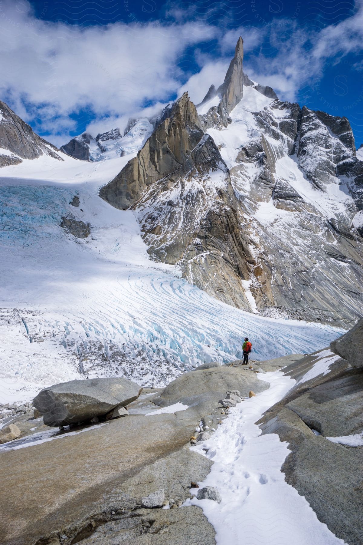 Distant hiker with red backpack observing glacier in el chalten patagonia