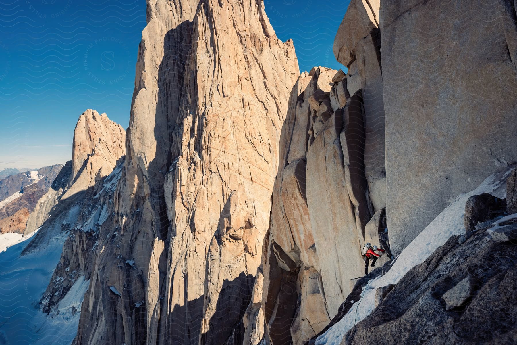 A mountaineer climbs snowy cliffs on the mountaintops in the morning