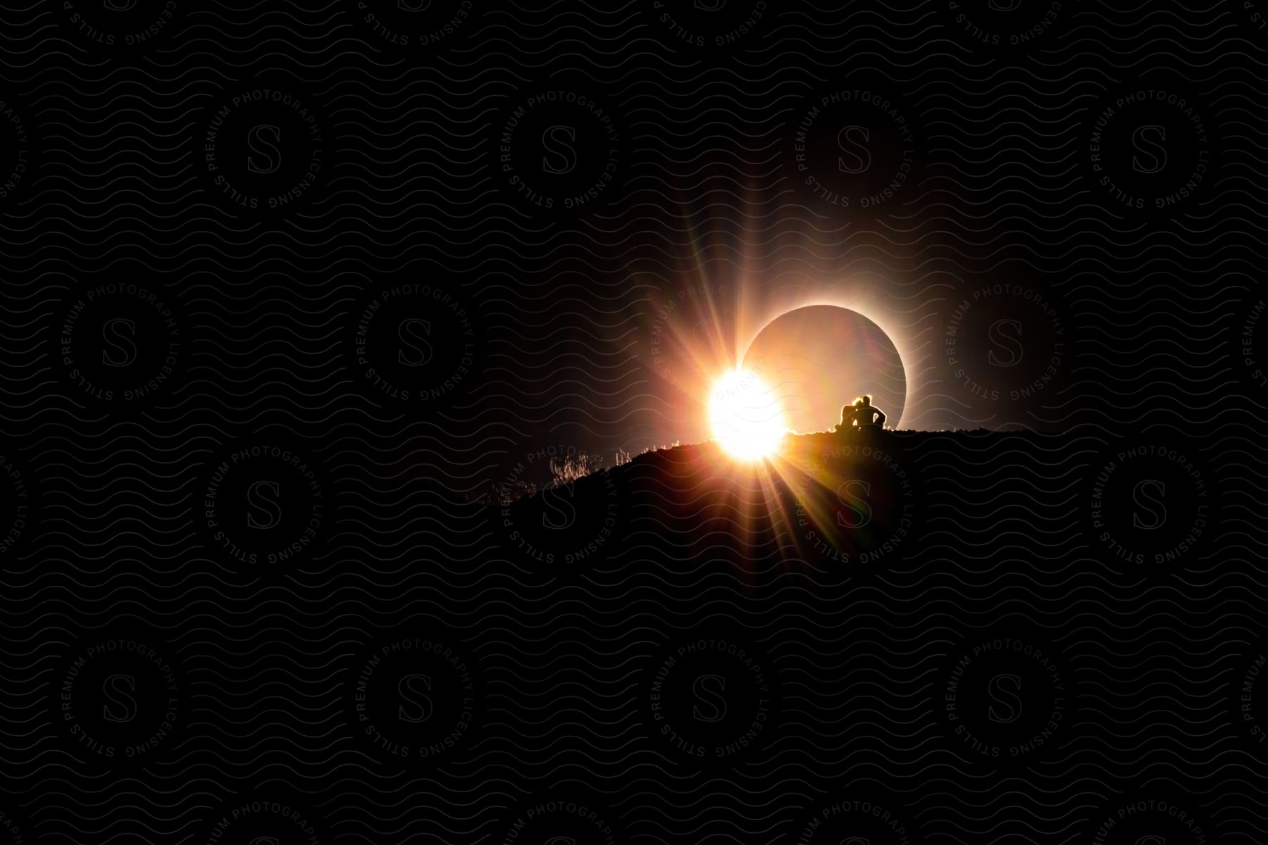 Couple sitting on a mountain watching a solar eclipse