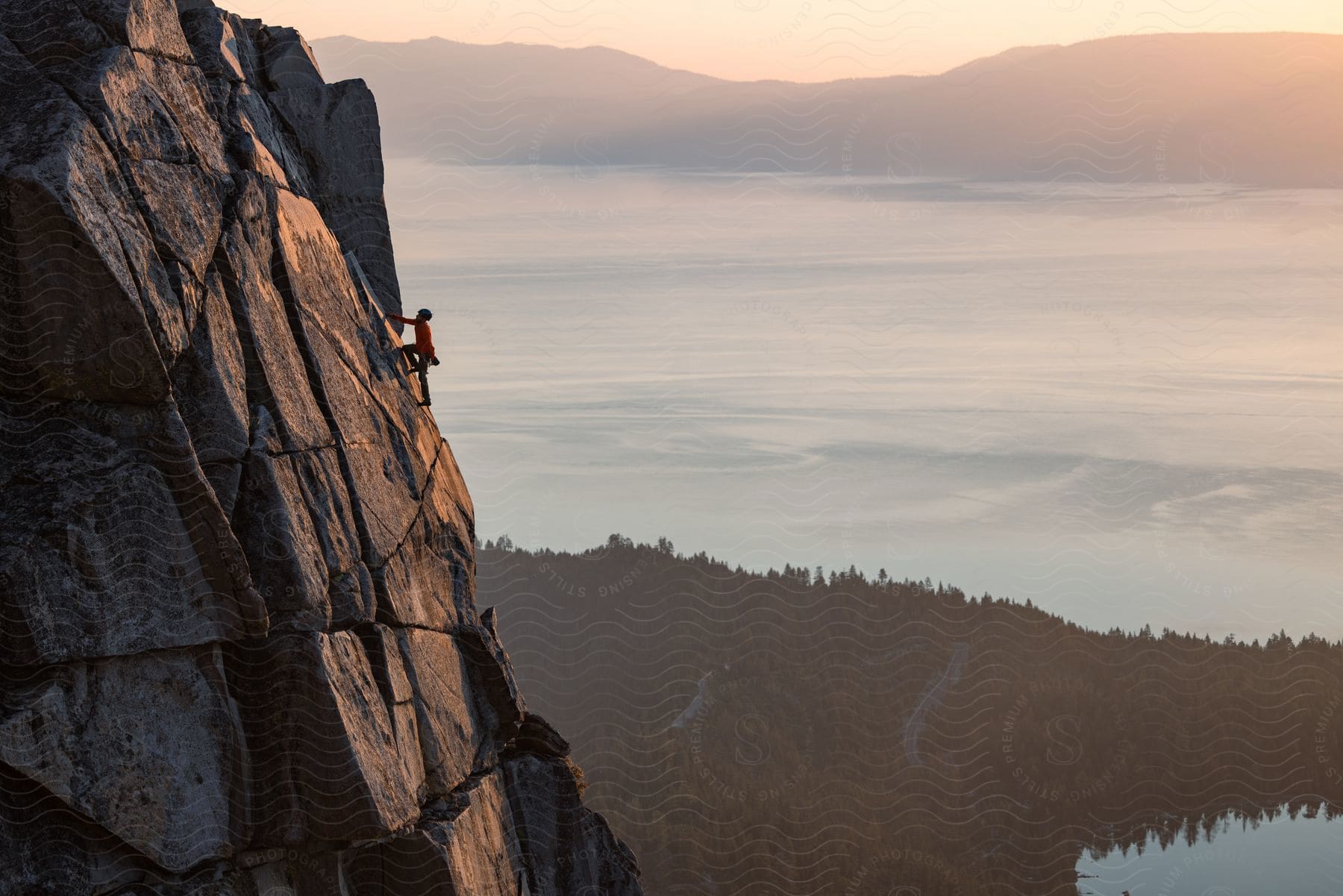 A person climbing a rocky cliff near a lake in south lake tahoe