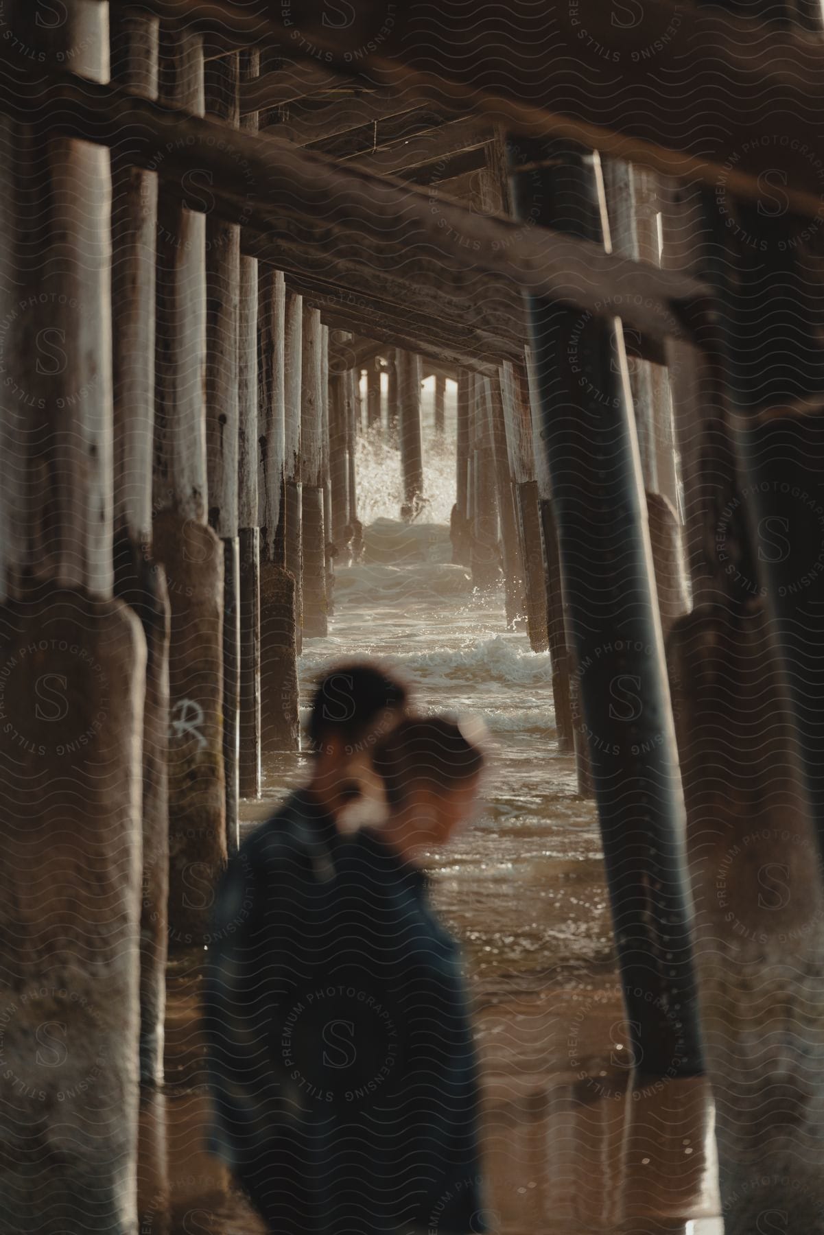 A couple walks under a pier in shallow water
