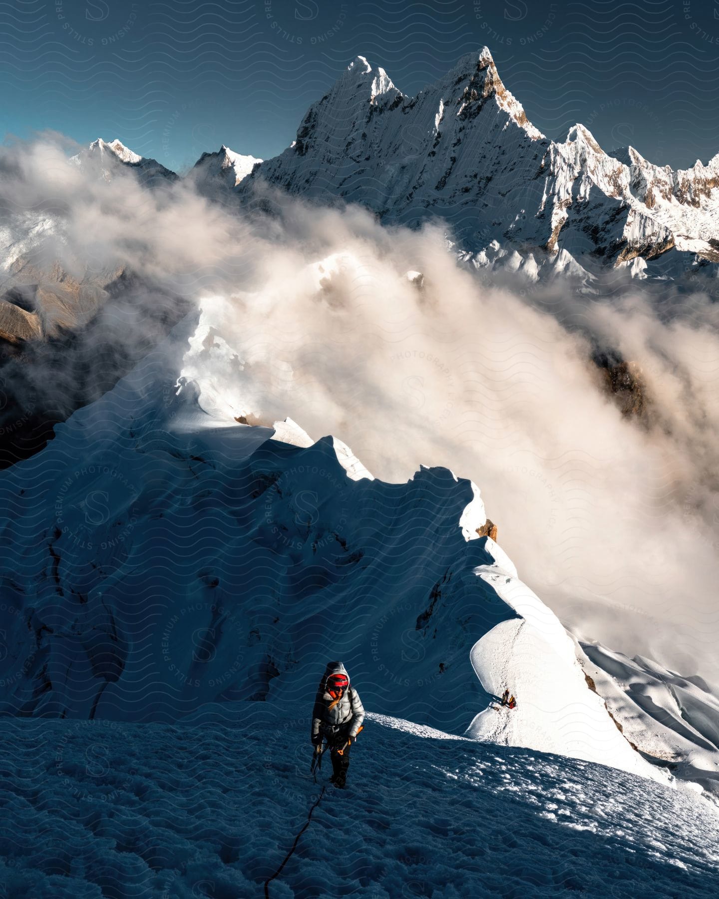 A hiker climbs a snowy slope with a mountain in the background