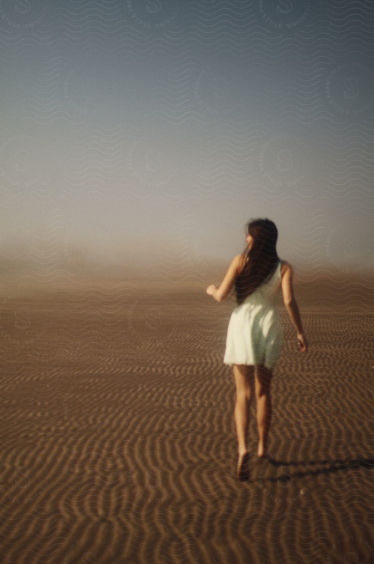 A woman in a white dress running on the sand