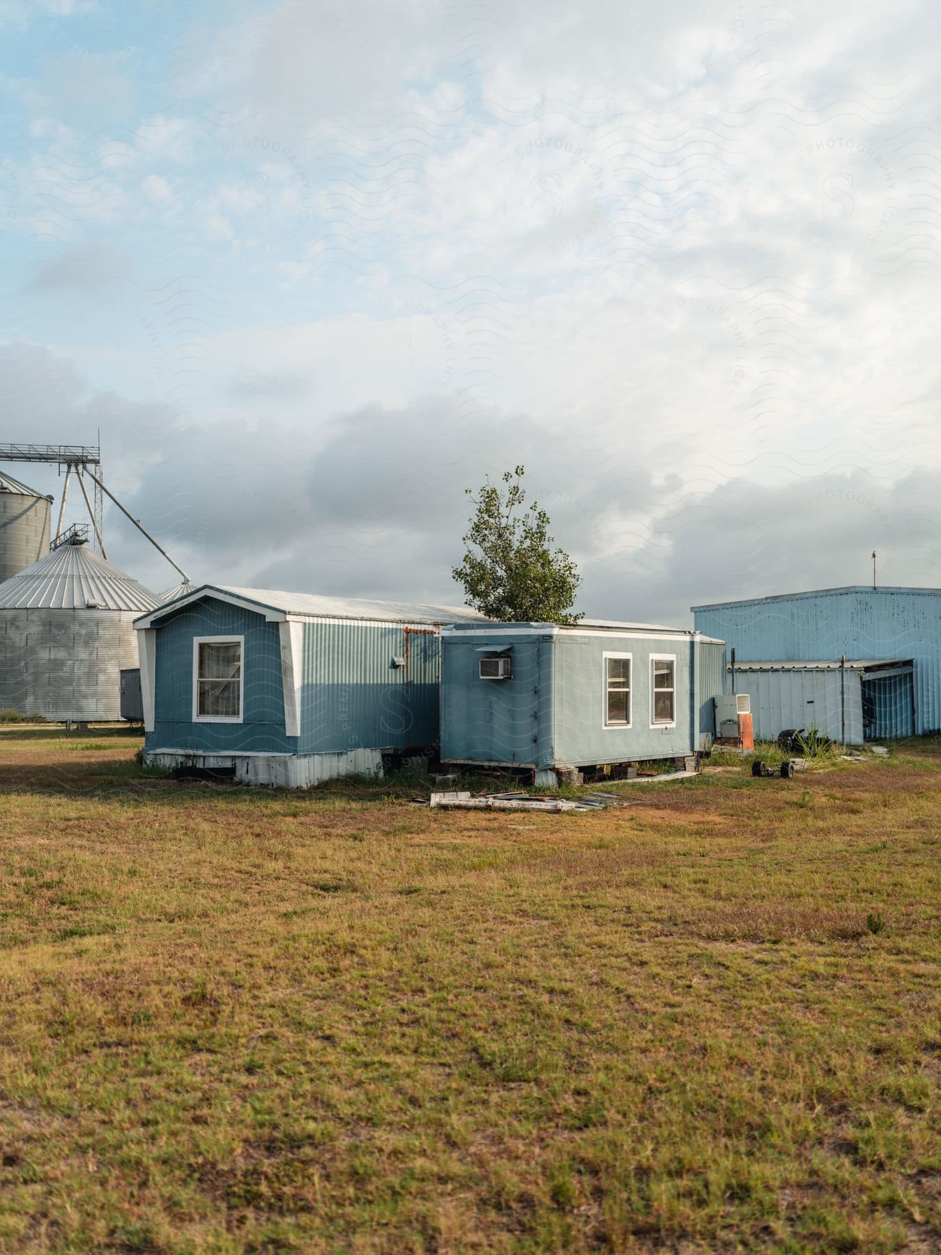 A field with industrial buildings and clear clouds in the sky