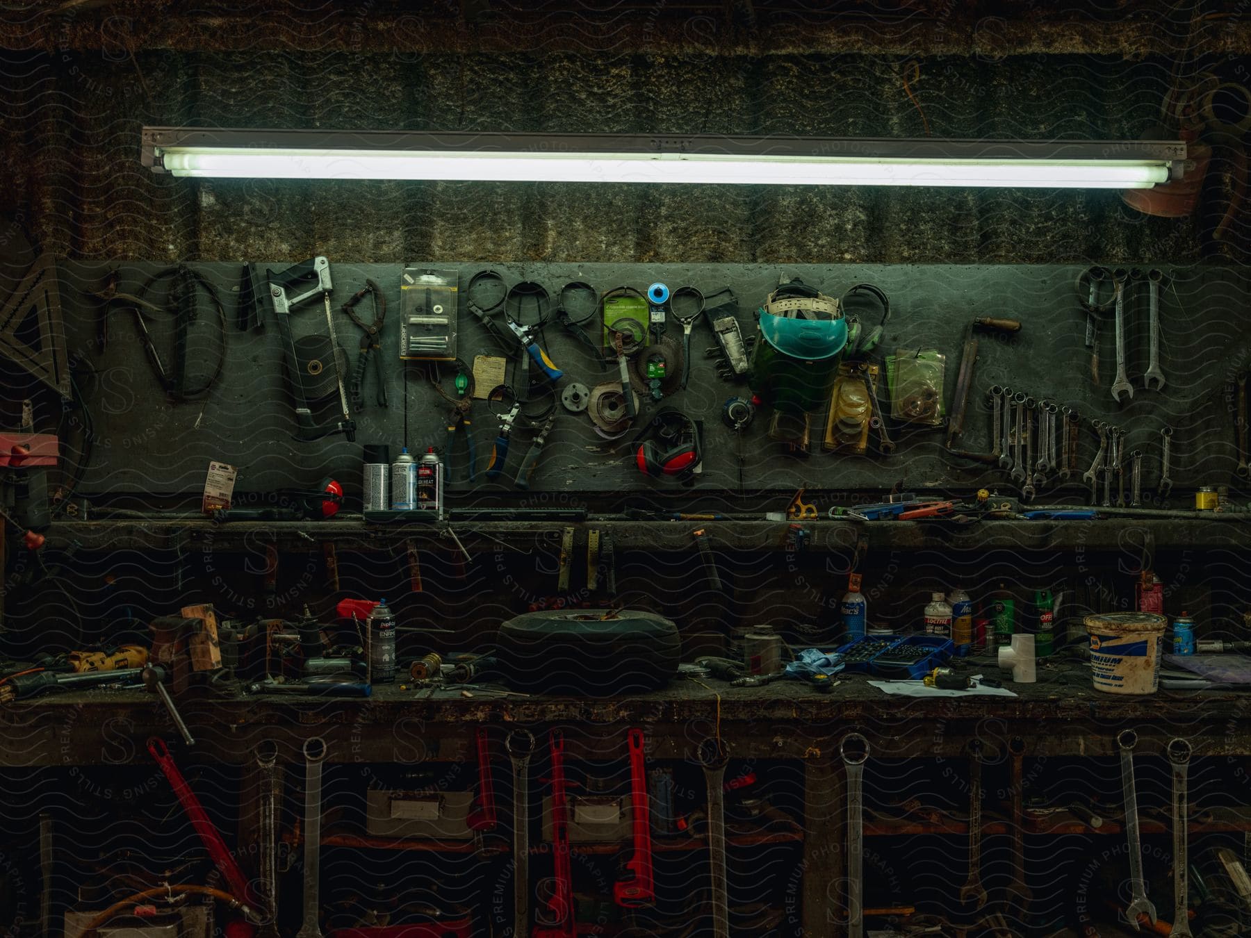 Tools hanging from the wall over a workbench inside a dimly lit workshop