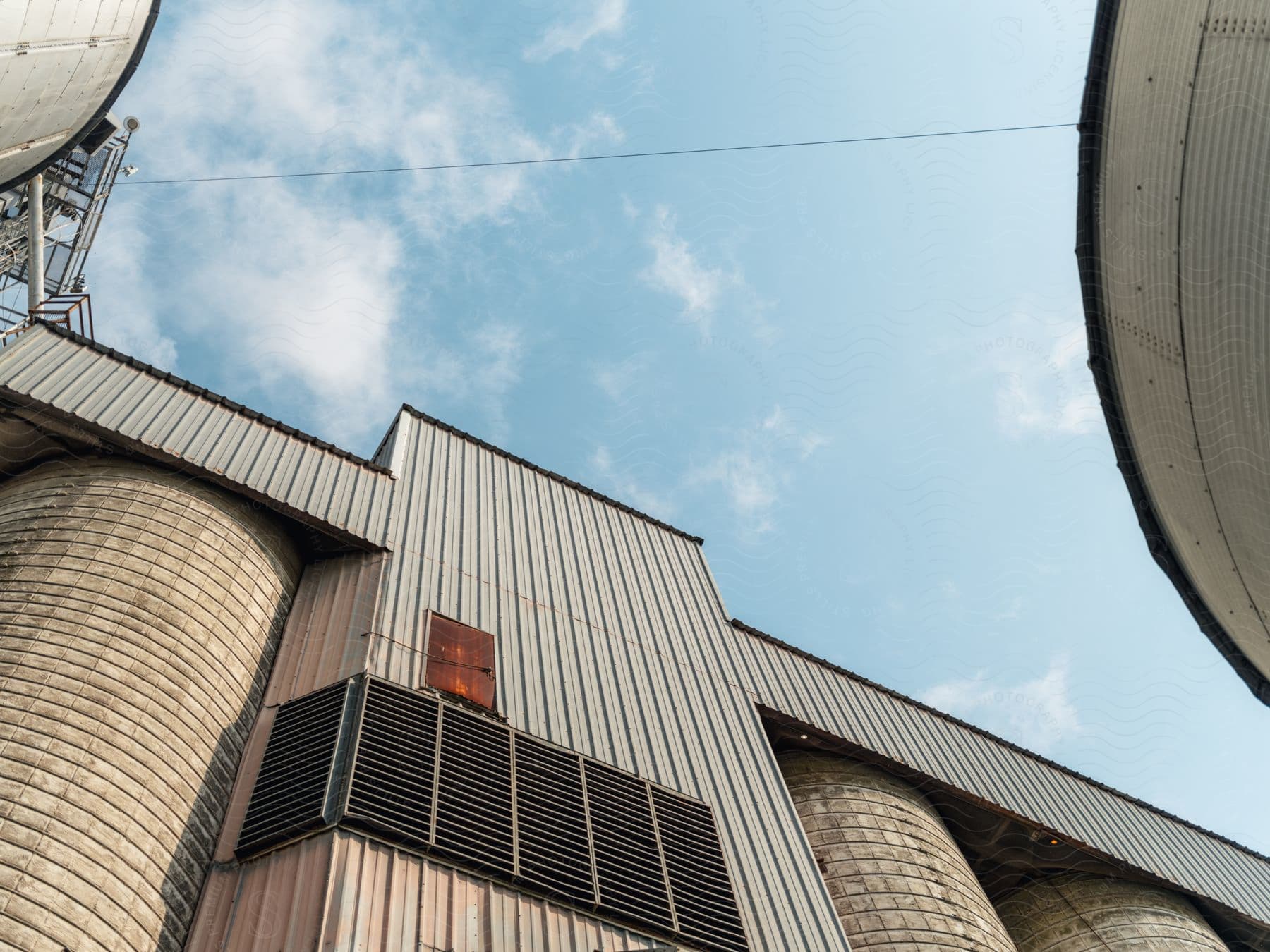 A row of silos at a grainery under a blue sky viewed from the ground up