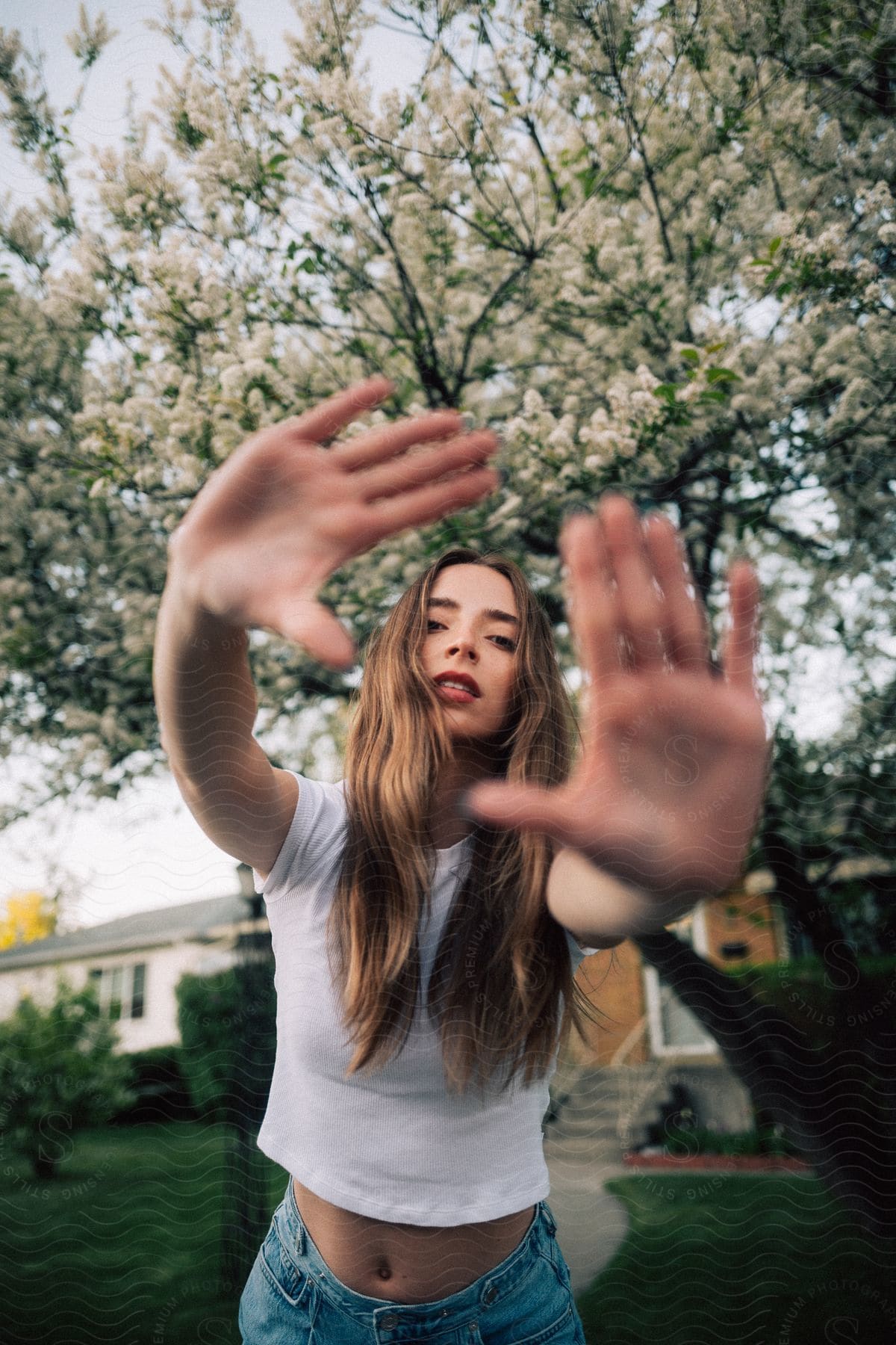 Stock photo of a young woman holds her hands up to the camera framing her own face