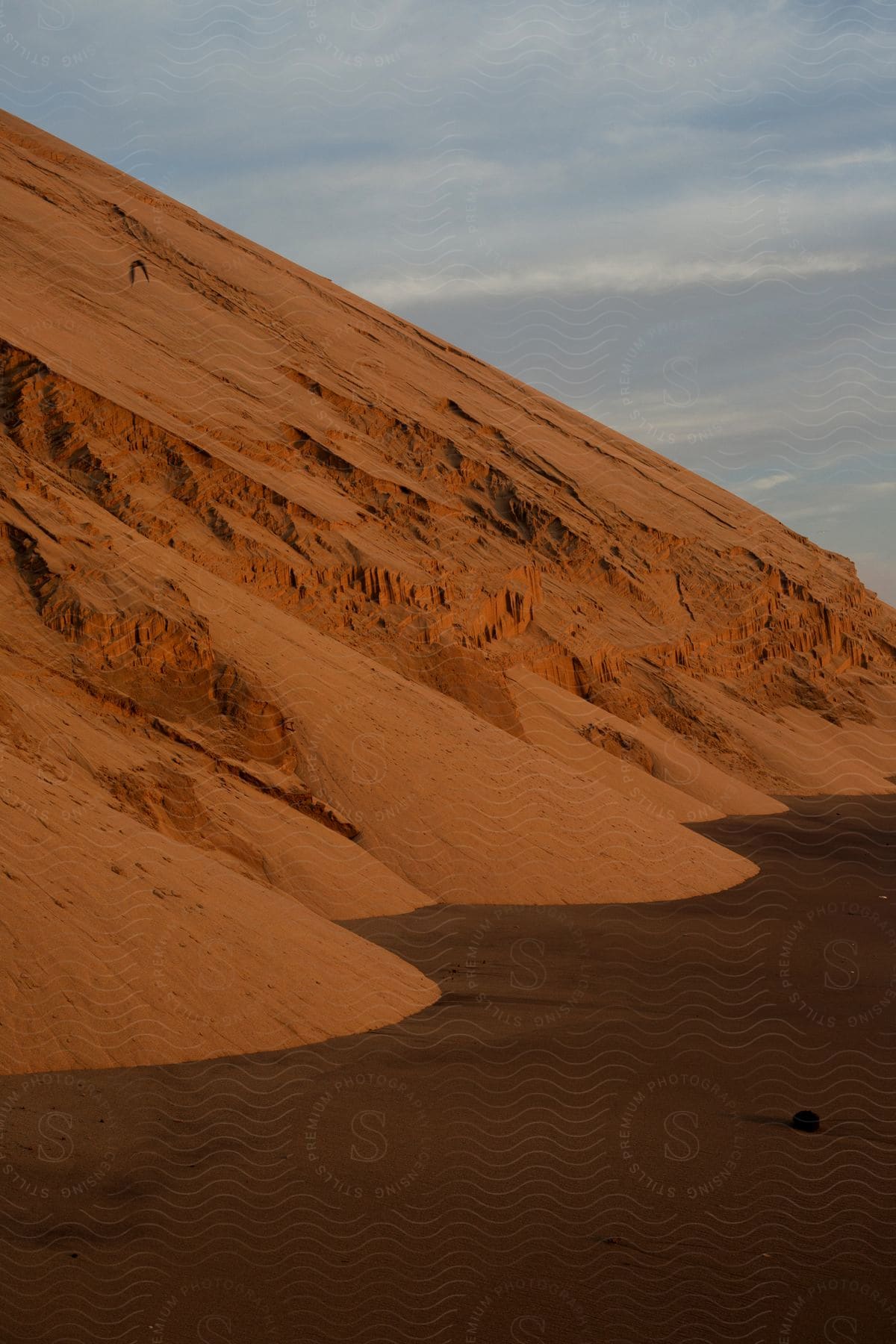 A barren desert landscape with sandy dunes under a cloudy sky