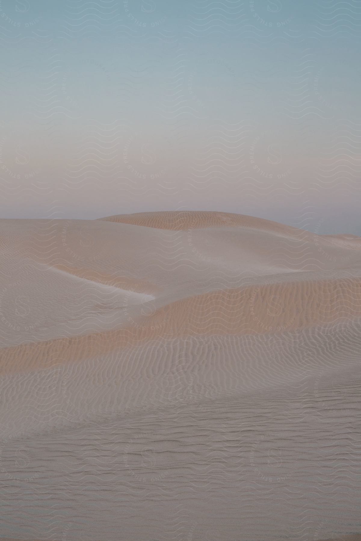 A sandcovered dune landscape with hills in an outdoor desert setting
