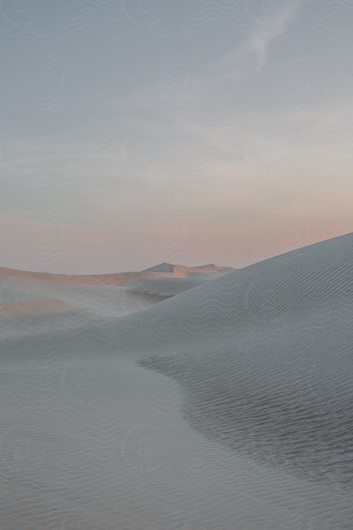 A desert landscape with a sloping sand dune under a clear sky