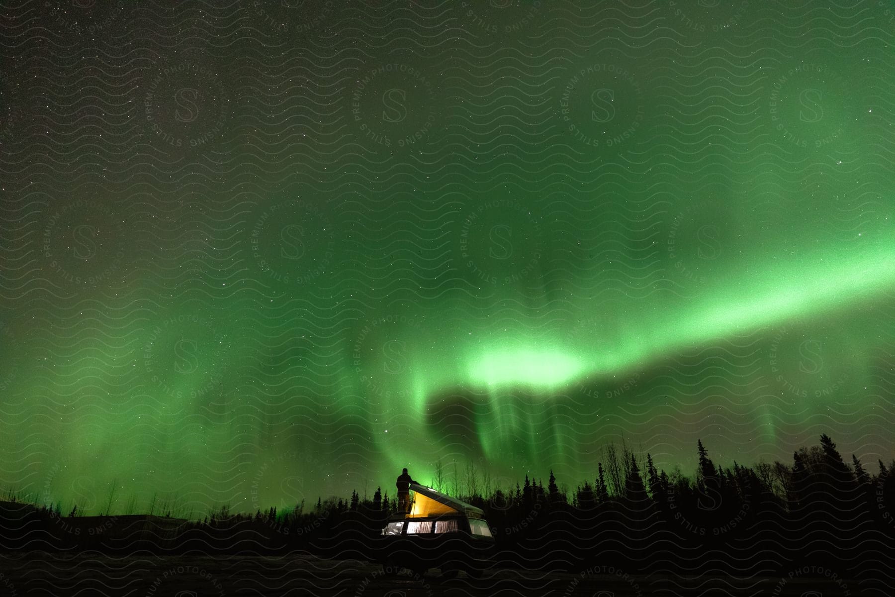 Person looking at the northern lights sky from a van in alaska