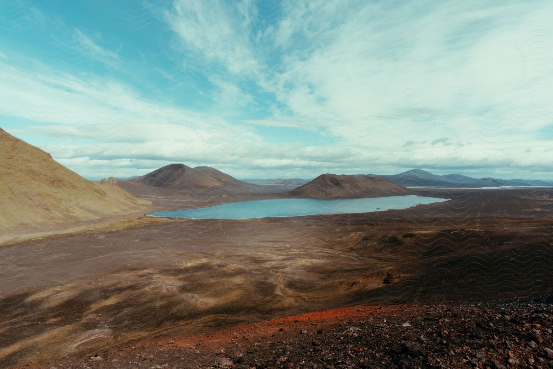 A lake nestled in the foothills of a rocky mountain range under a cloudy sky