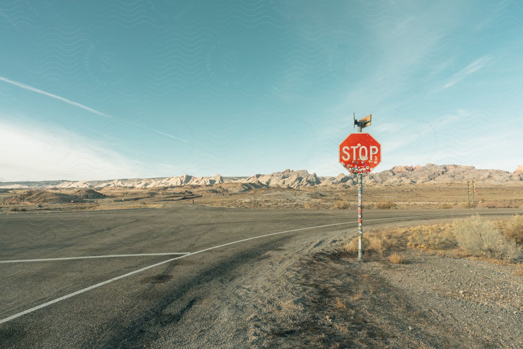 Road with road sign in a desert landscape with mountains on the horizon