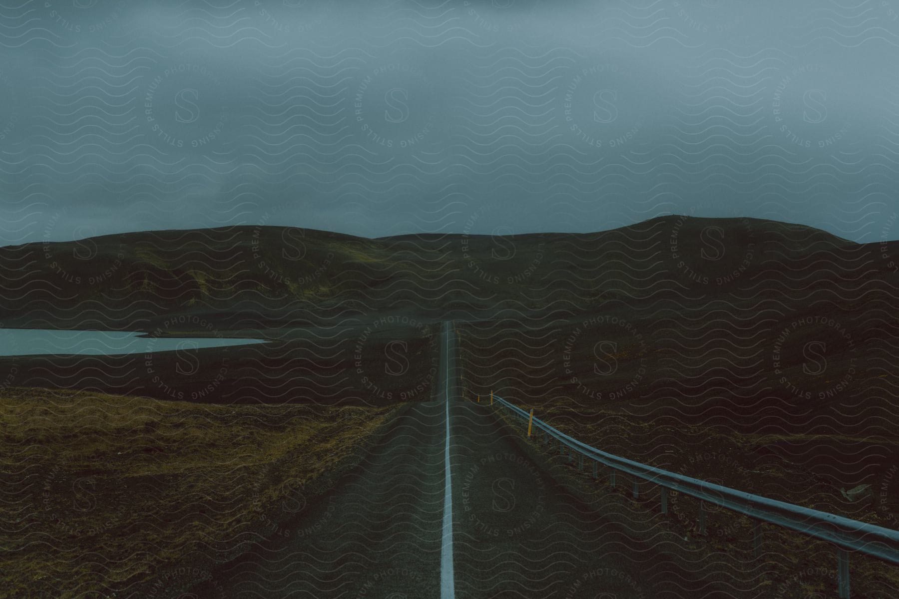 A highway through the hills near a lake on a cloudy morning