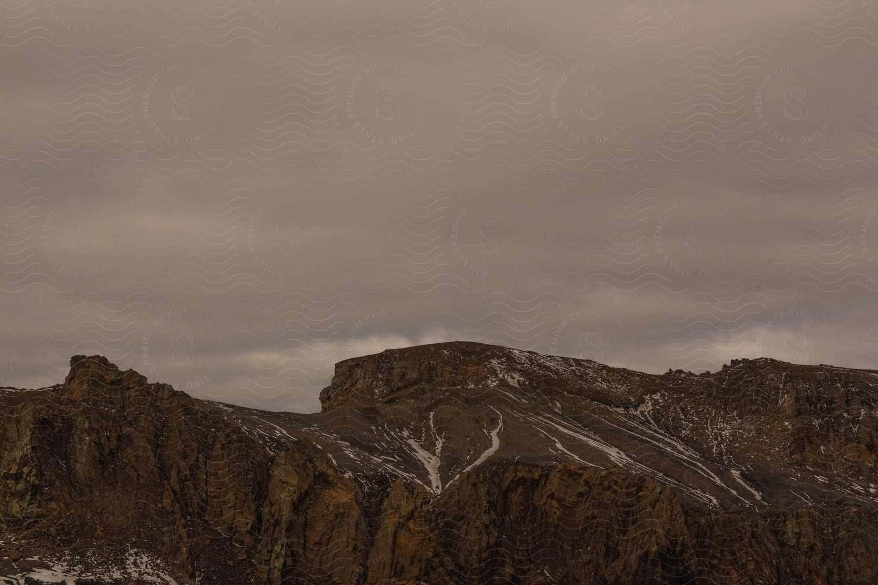 Mountain range with streaks of snow on a cloudy day lacking vegetation