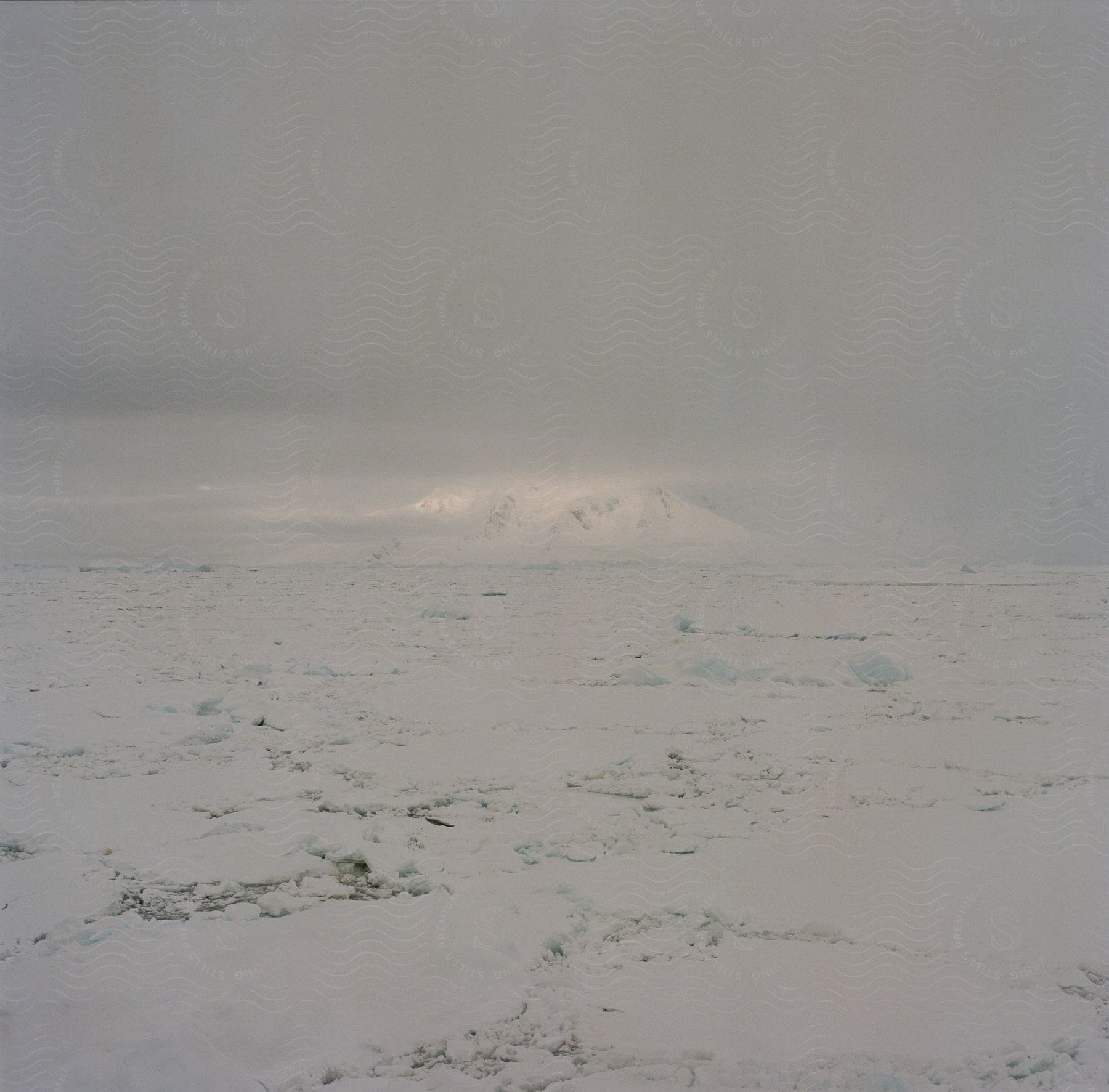 Ice cap stretches across vast landscape with distant mountain on frozen horizon