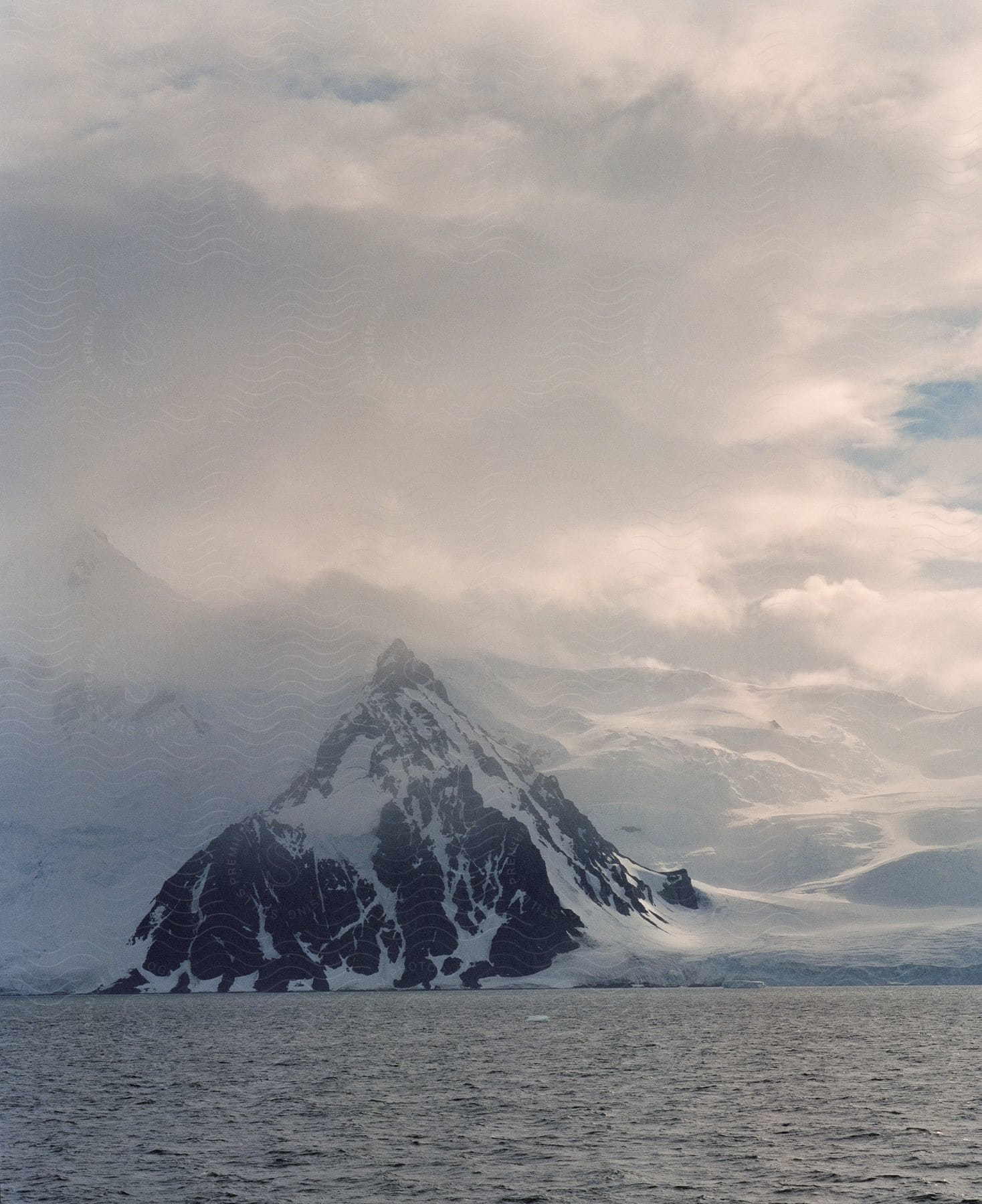 Snowcovered mountain standing tall near ocean creating picturesque scene with mystical foggy ambiance