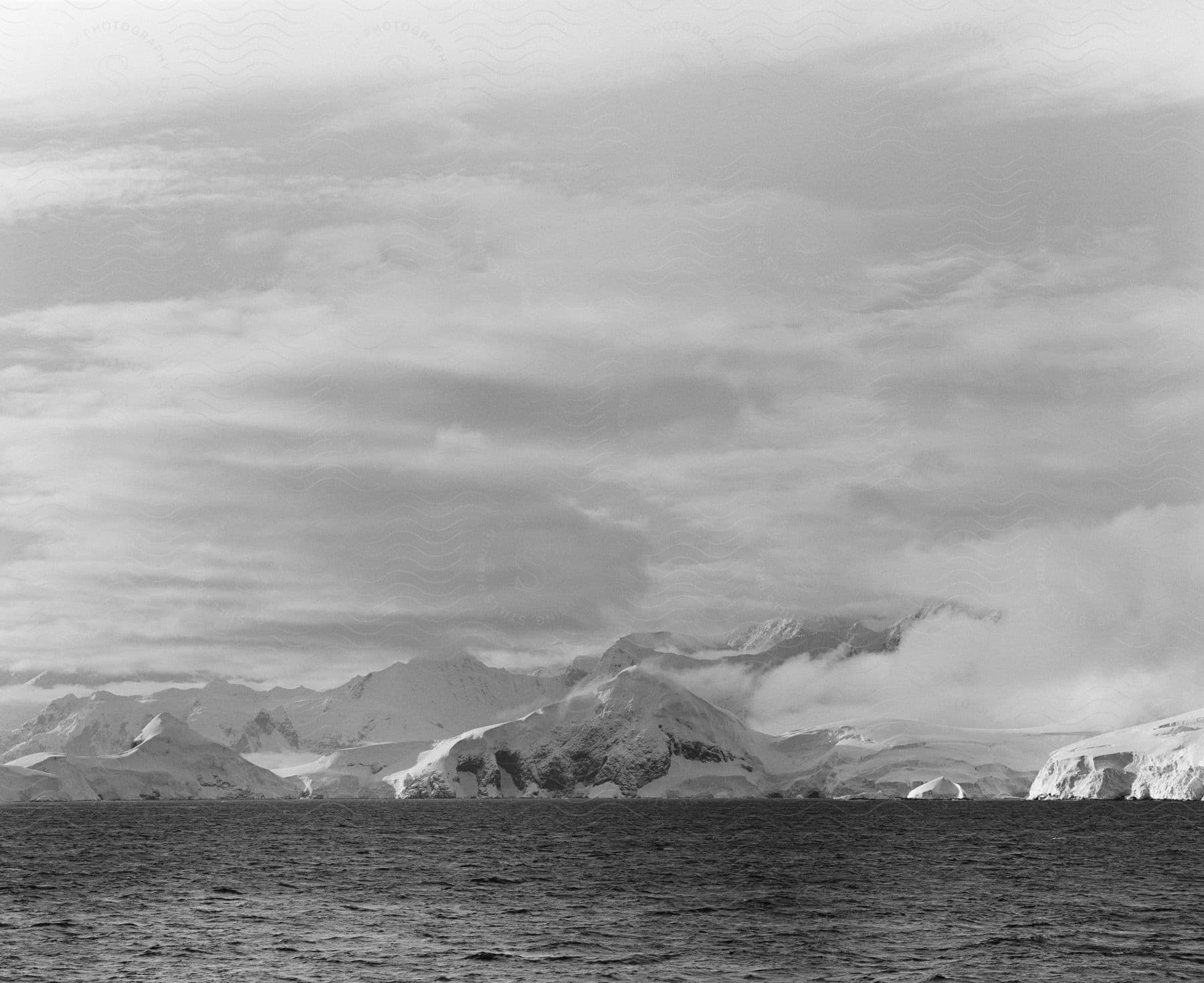 Antarcticas snowcovered land appears on a cloudy day with calm seas