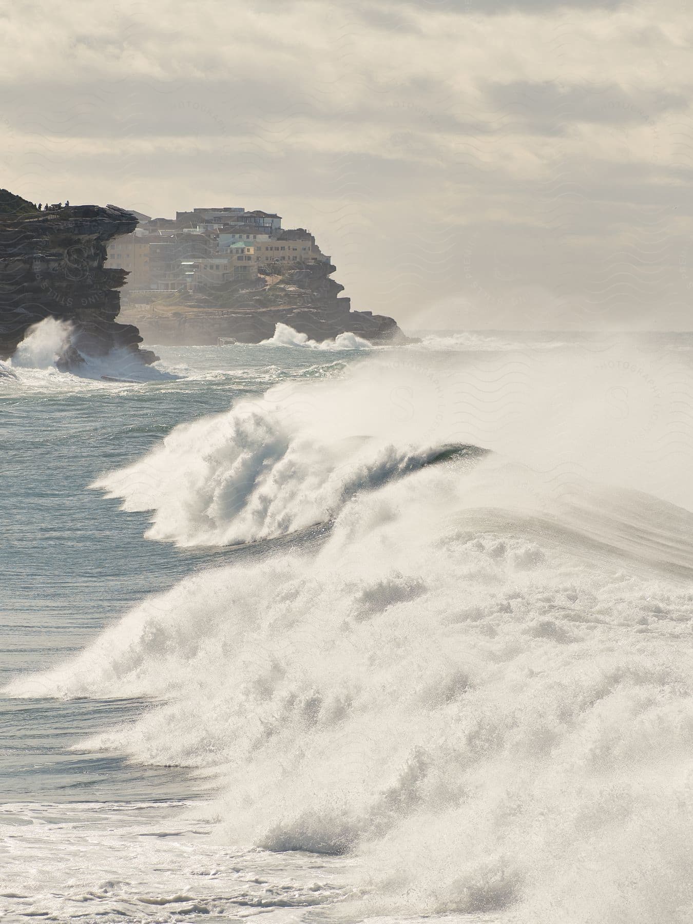 A beach with bubbling water waves and beach houses in the distance