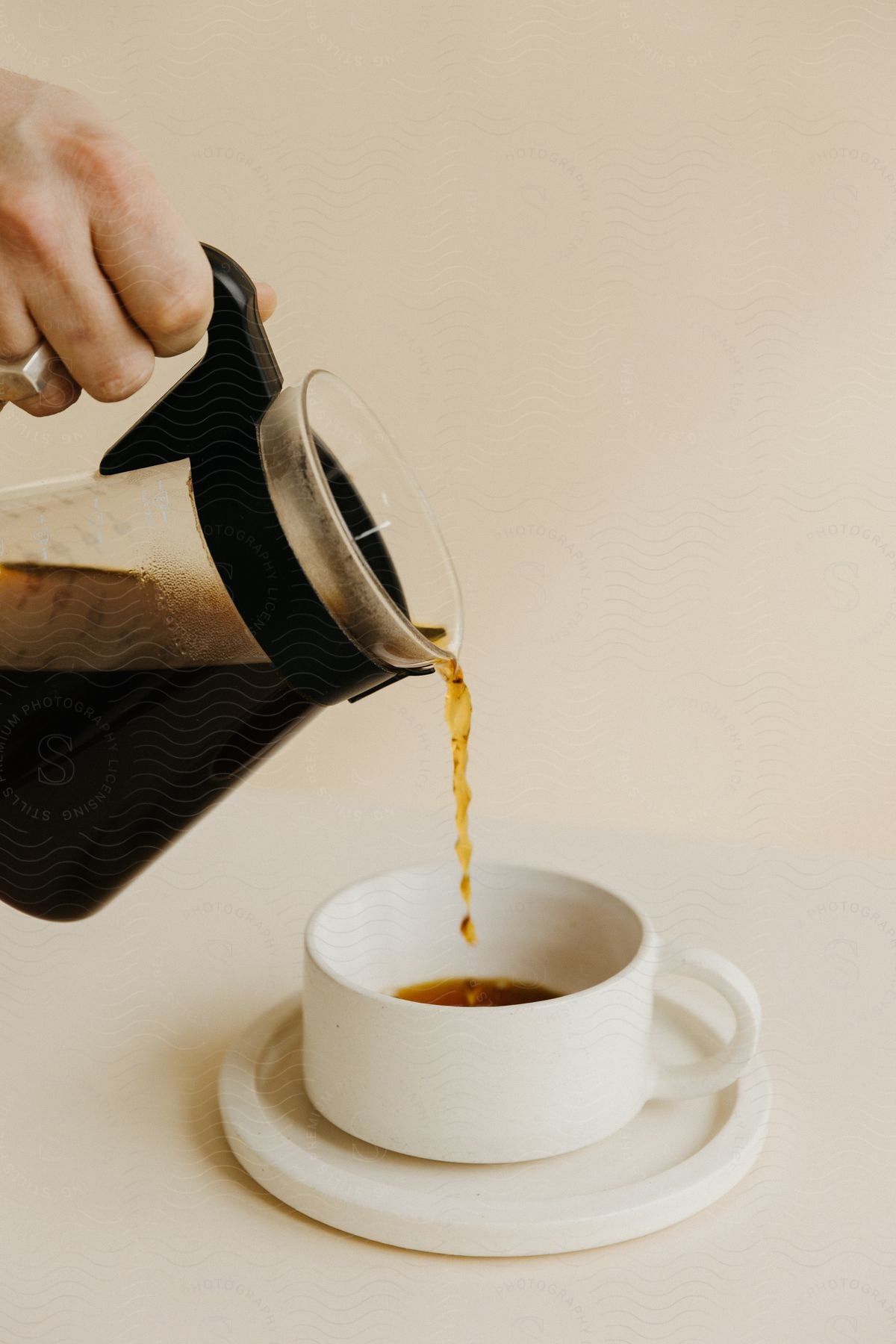 Hand pouring coffee into a small cup