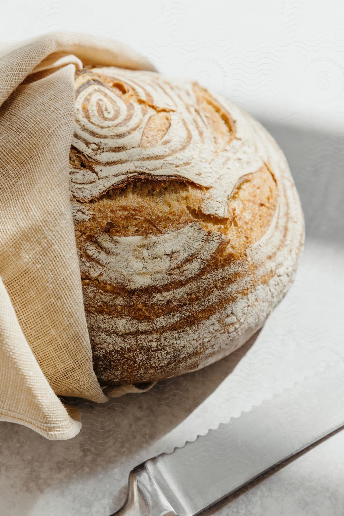 A homemade bread wrapped in a cloth and a knife