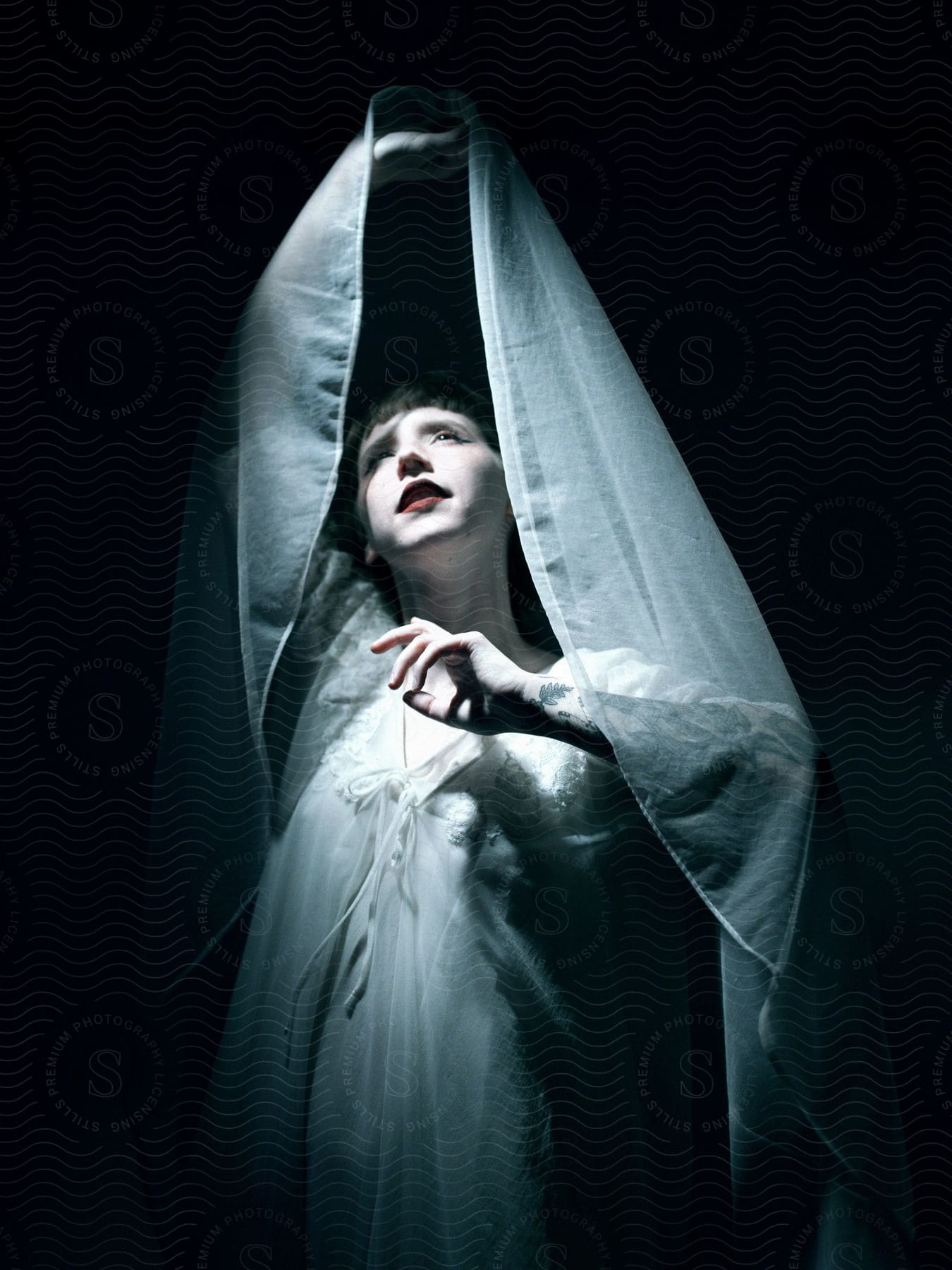A woman in white gesturing with a veil
