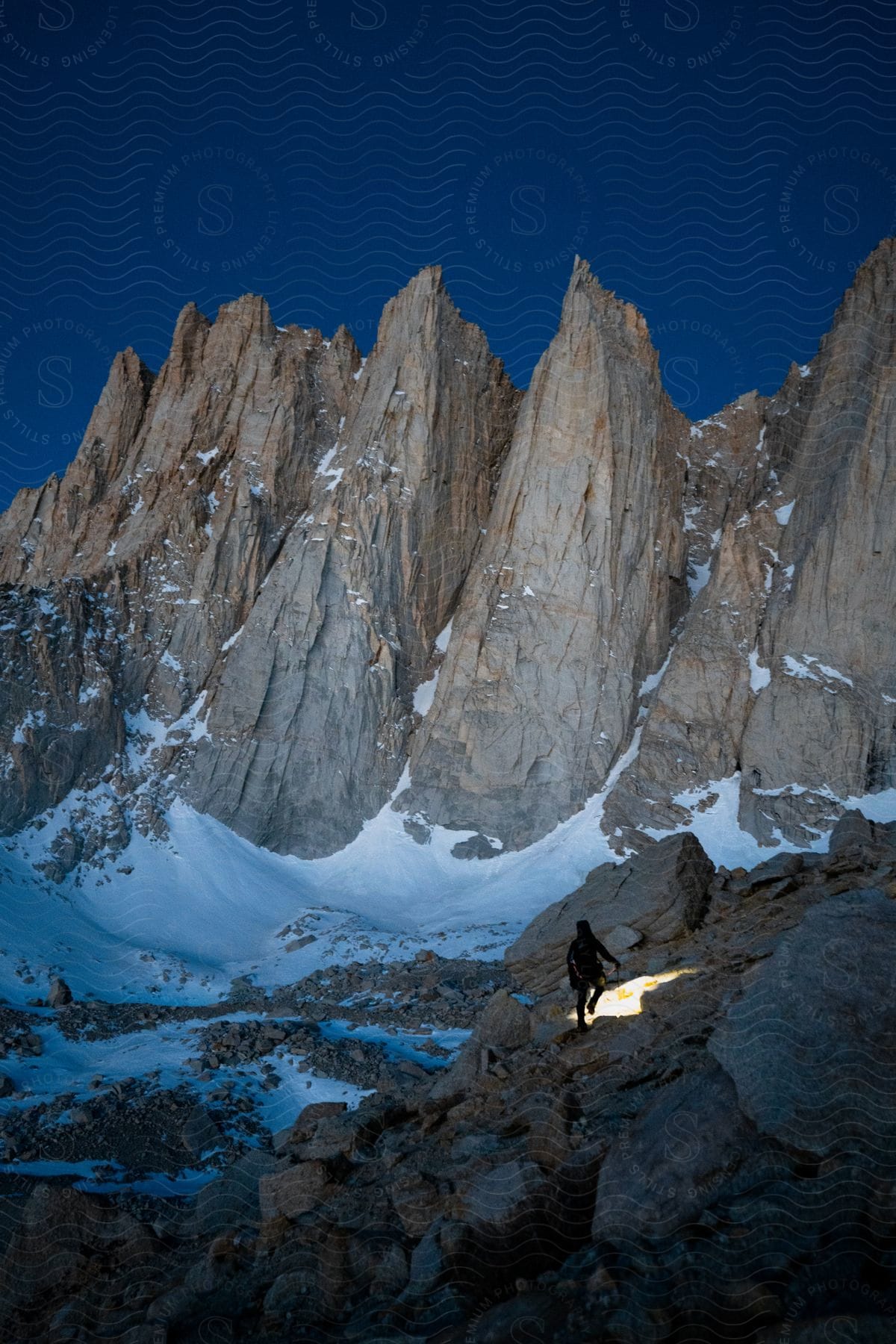 Person shining flashlight on rocks near mountains under blue sky