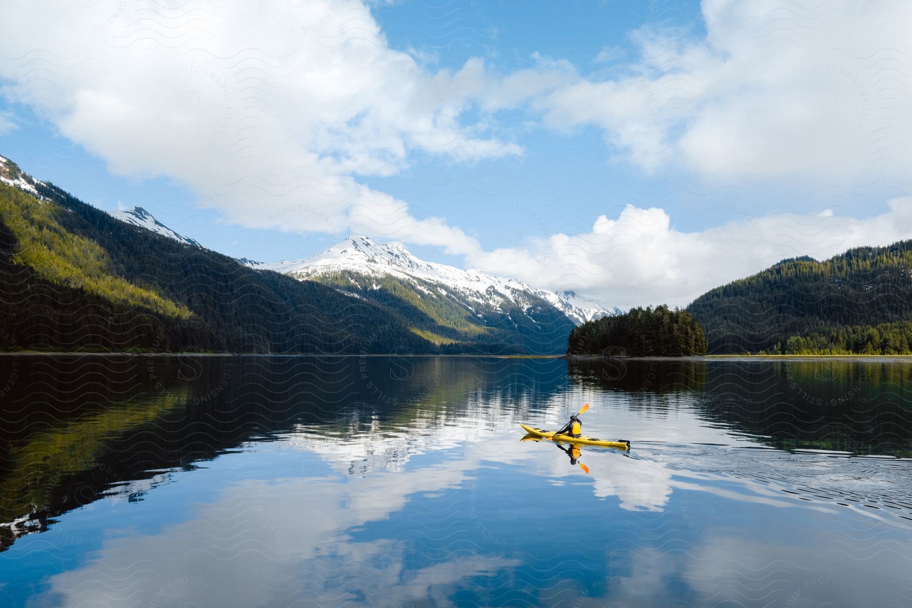 A person in a boat on a lake surrounded by mountains