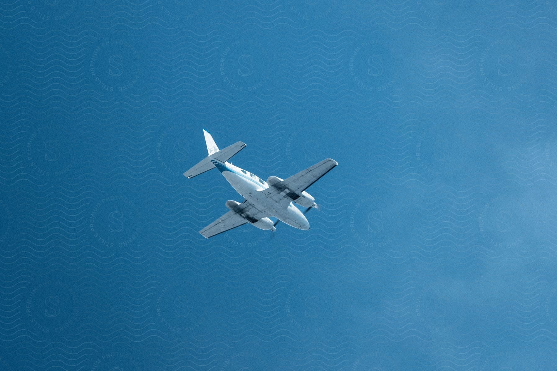 An airplane flies across a clear blue sky in sunlight