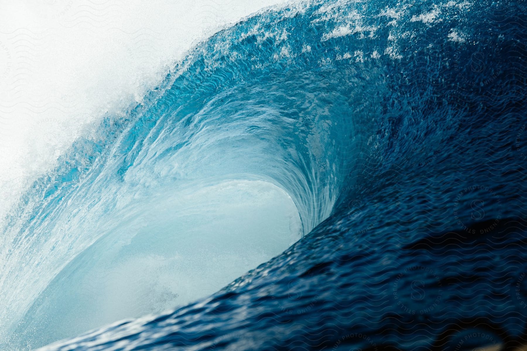 A huge splashing blue wave curls as it rolls into shore at an exterior location during the day in spring or summer