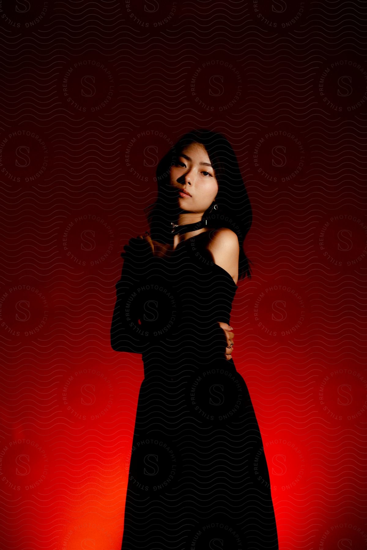 Asian girl in black formal dress against red background with red lighting