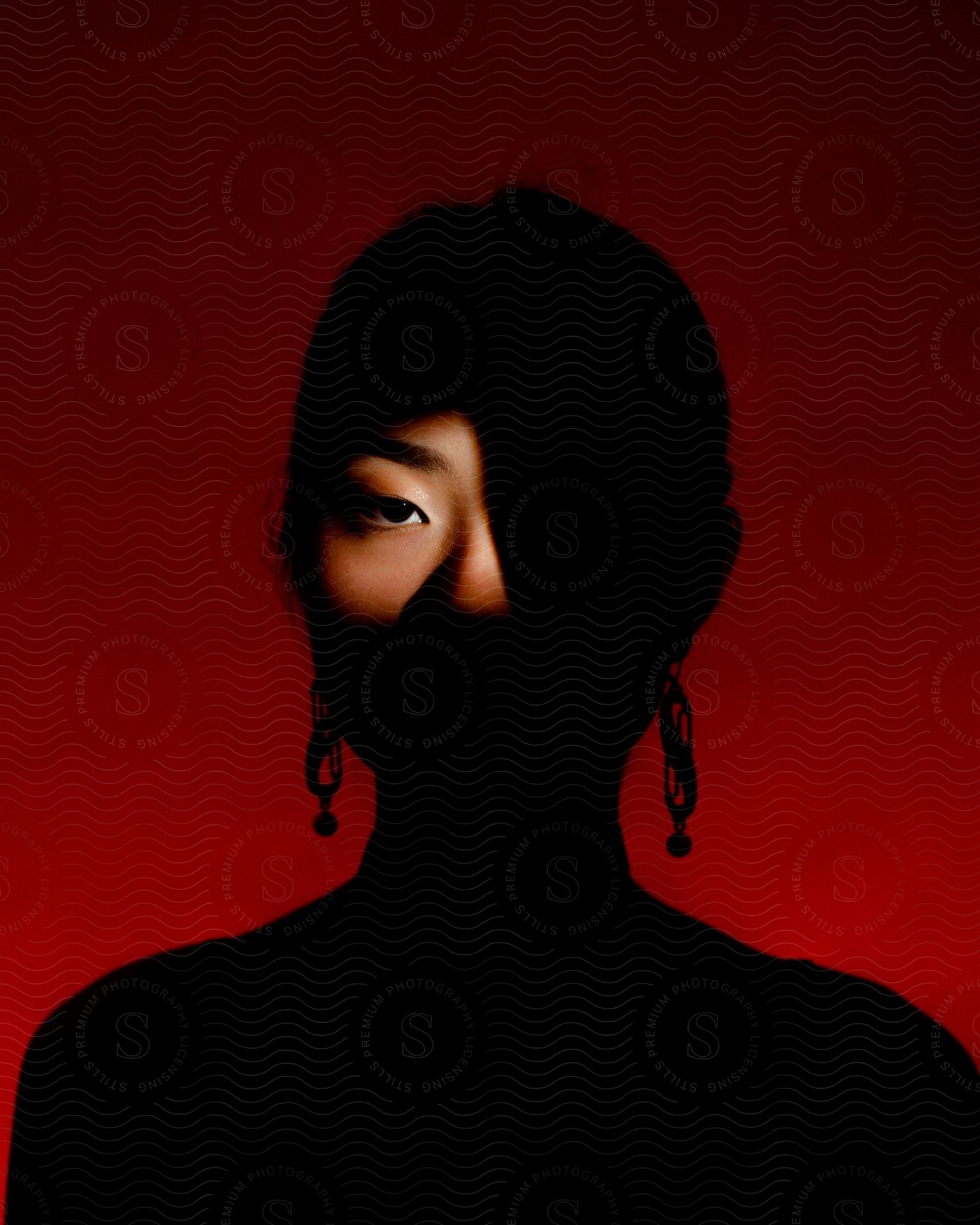 A womans silhouette with only her right eye illuminated