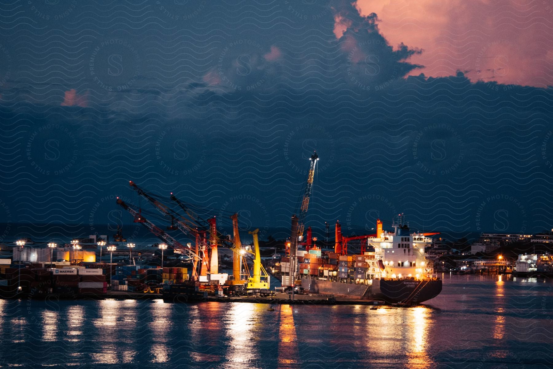 A waterfront scene at dusk with buildings boats and a pier