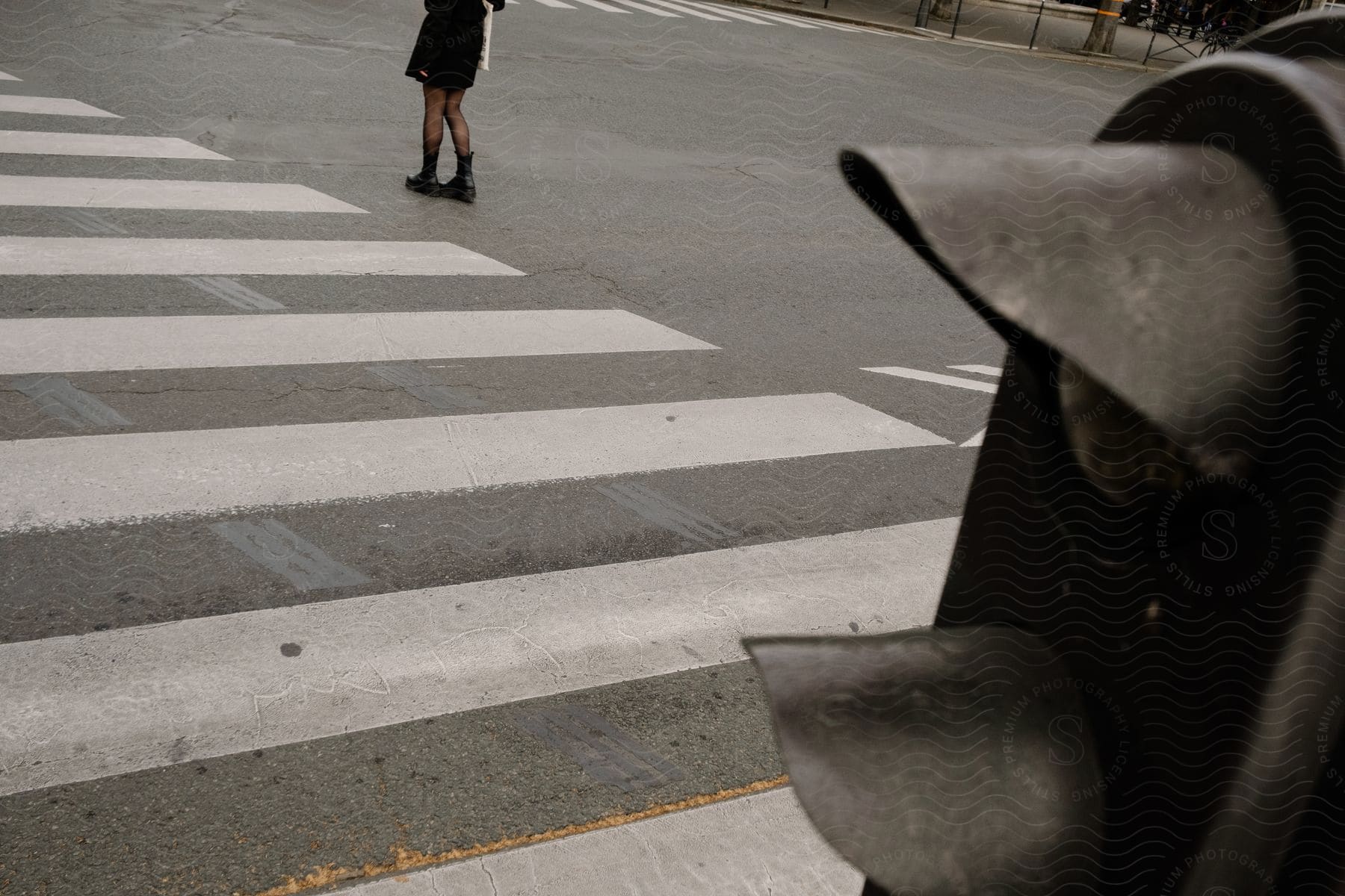 A woman in fishnets stands next to a crosswalk with a stop light in the foreground