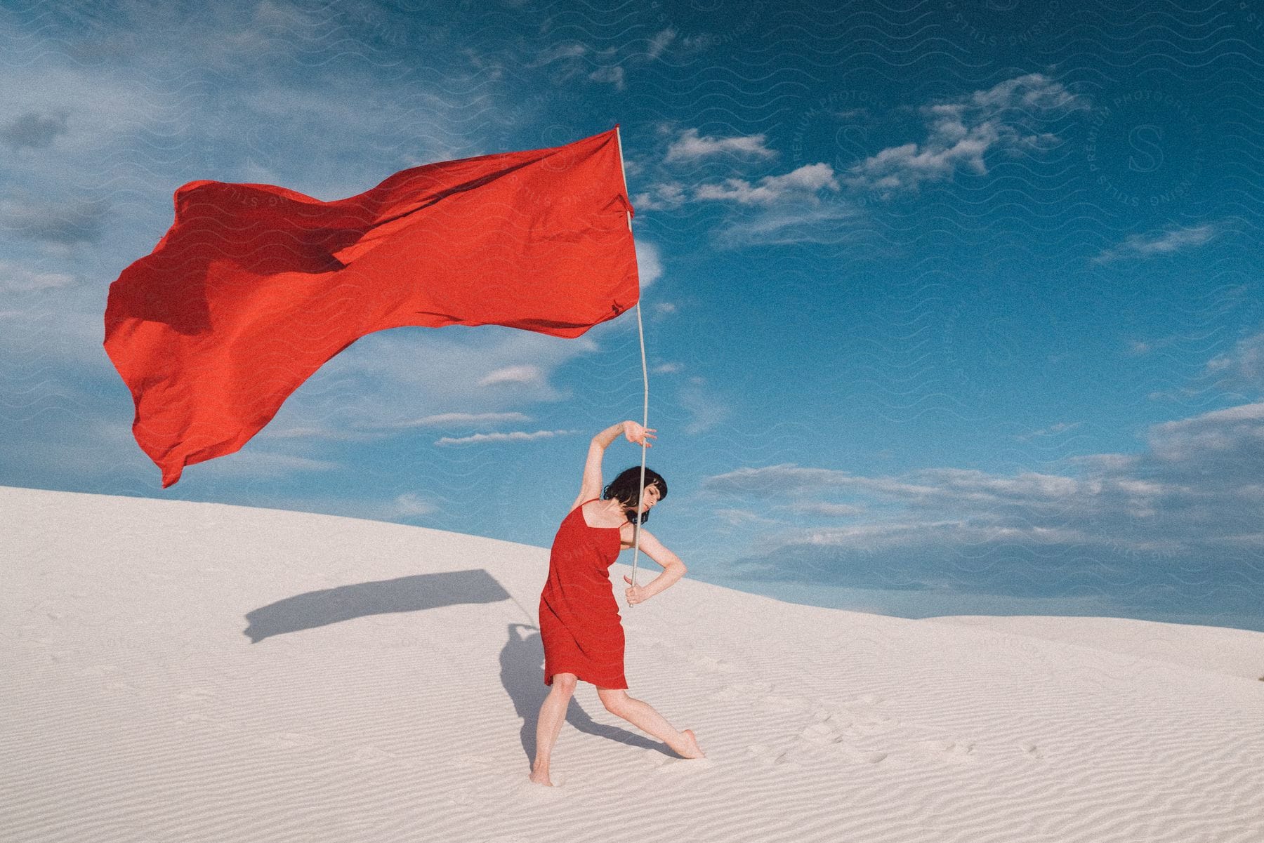 A woman standing in the desert with a flag in hand